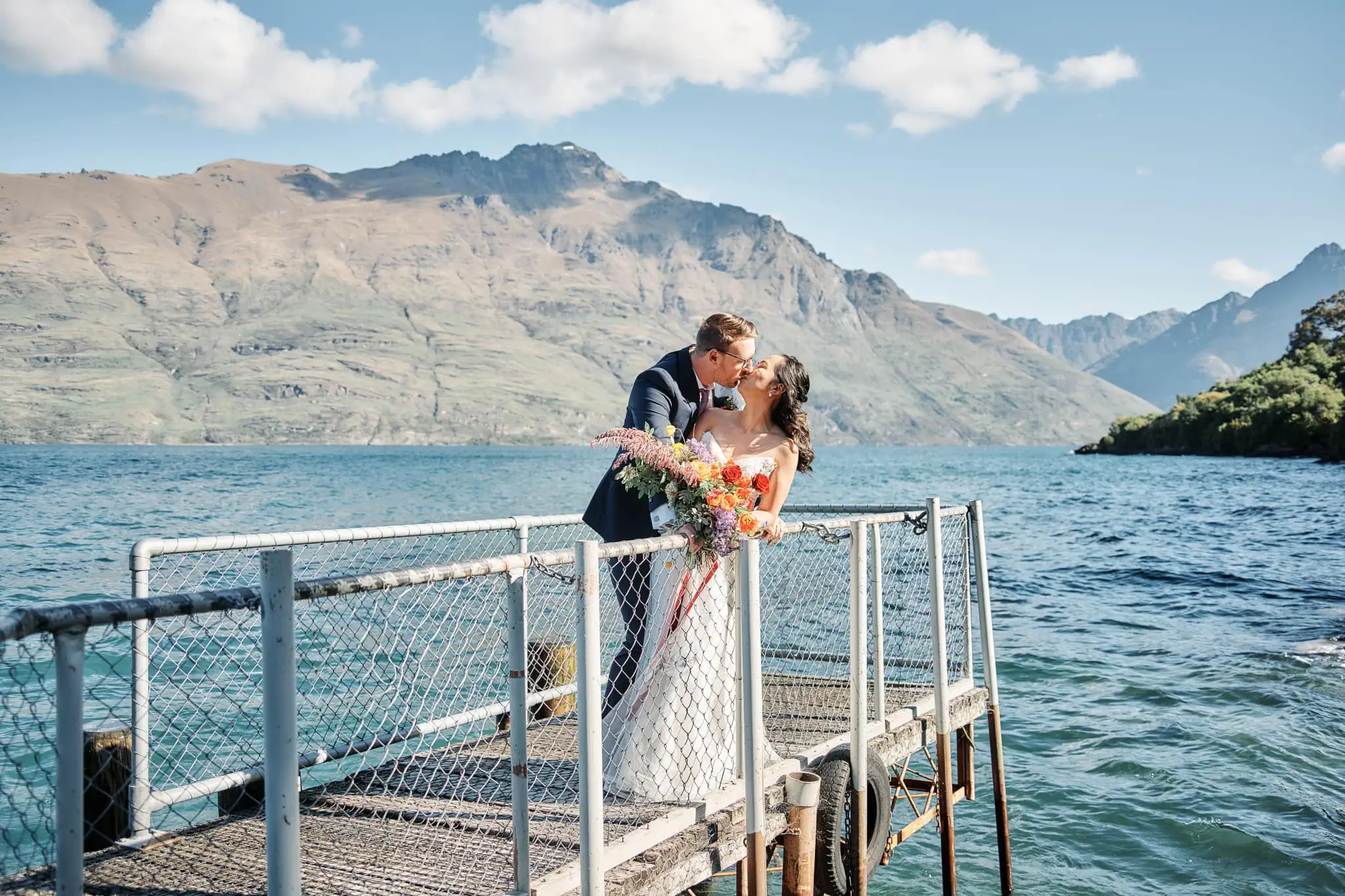 Ace and Alex share an intimate kiss on a dock during their Moke Lake pre-wedding shoot in Queenstown, New Zealand.