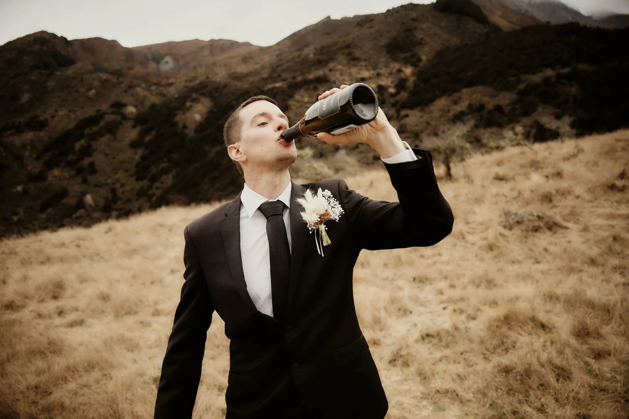 A man in a suit drinking from a bottle during Michelle and Vedran's Rees Valley Station elopement wedding.