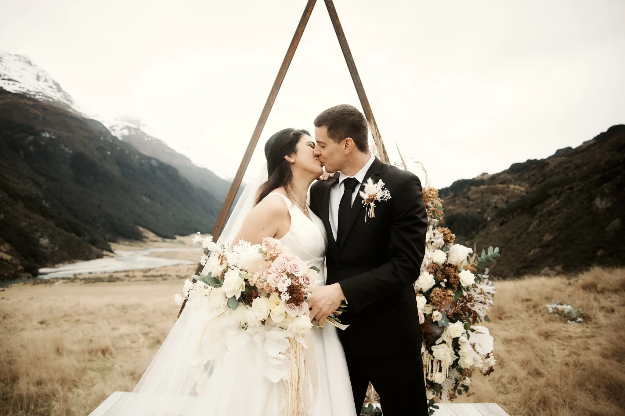 Michelle and Vedran share a romantic kiss under a wedding arch in the breathtaking Rees Valley Station for their elopement wedding.