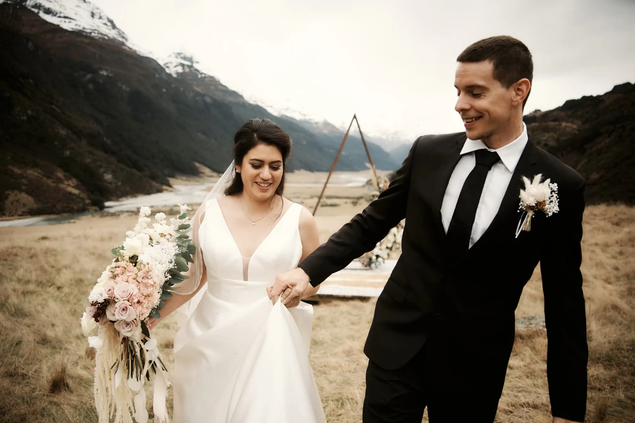 Michelle and Vedran's Rees Valley Station elopement wedding captures them walking through a field with majestic mountains in the background.