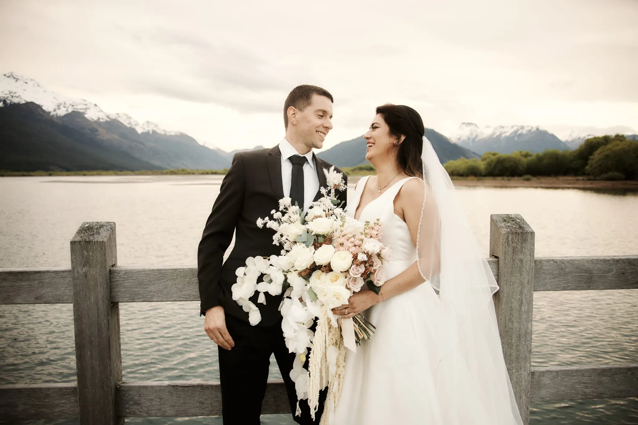 Michelle and Vedran's Rees Valley Station elopement wedding, with a bride and groom standing next to a lake with mountains in the background.