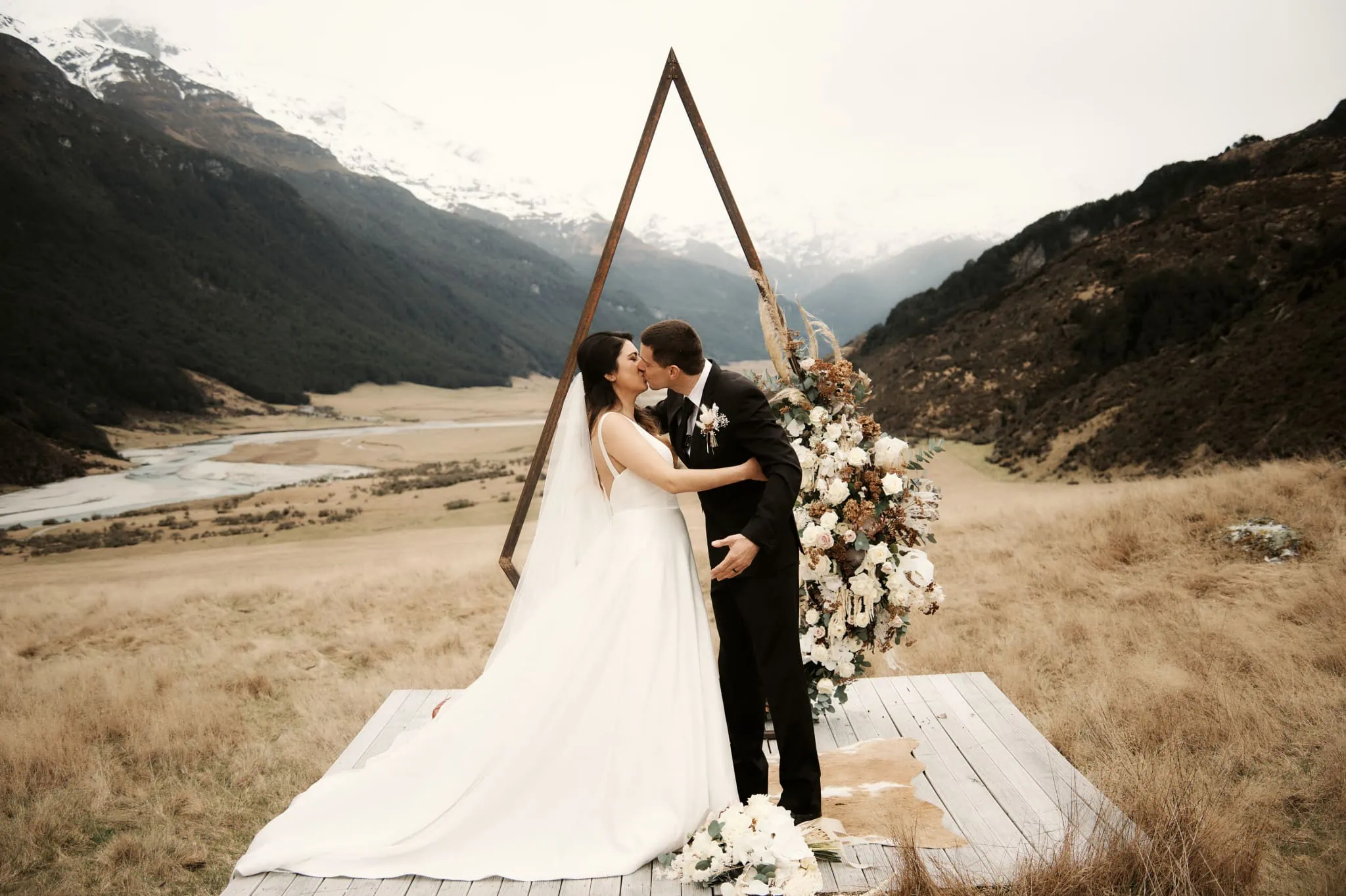 Michelle and Vedran share a kiss during their intimate Rees Valley Station elopement wedding, with stunning mountains as their backdrop.