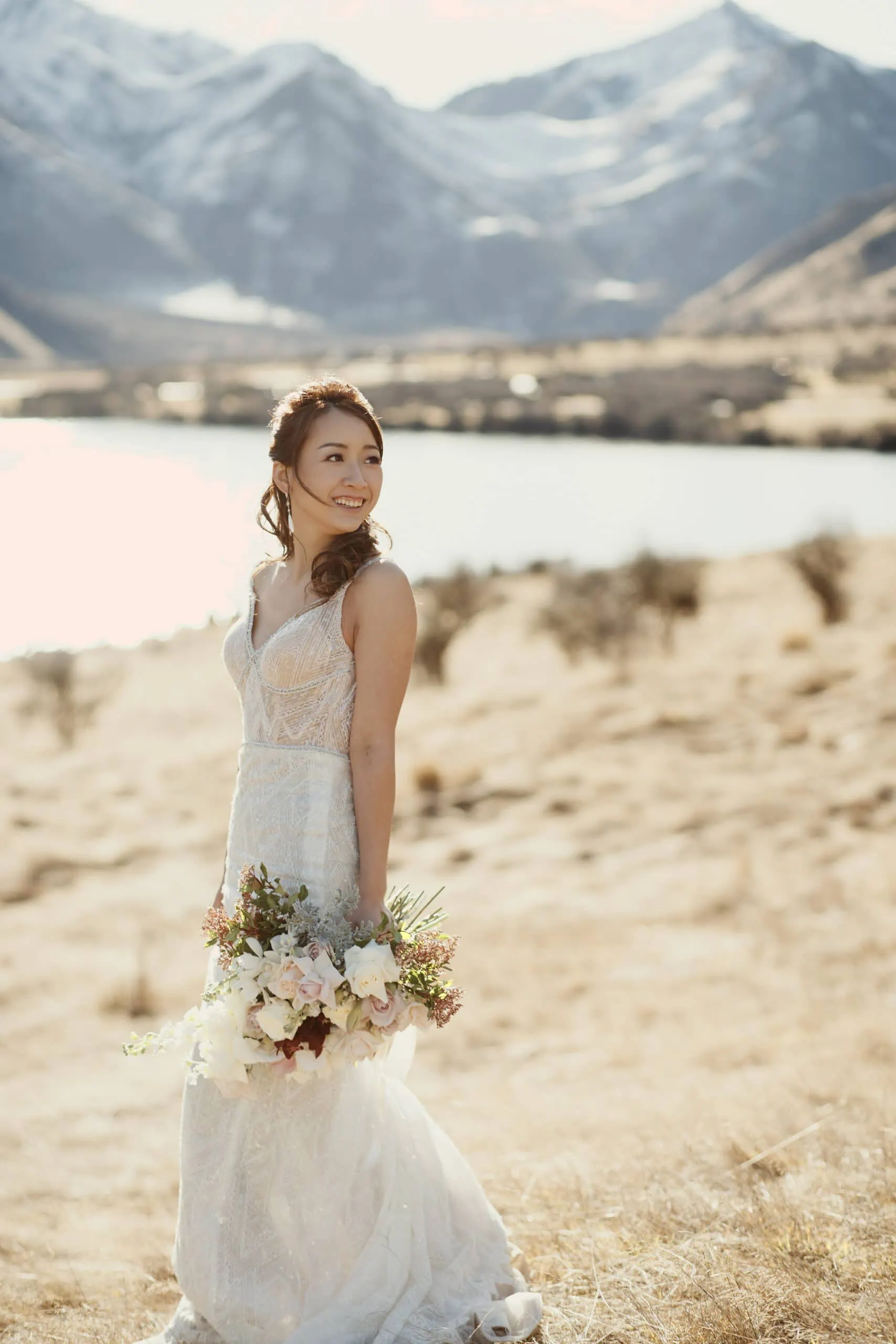 Stephanie and Carven's elopement at The Remarkables, with a bride standing in a field with mountains in the background.