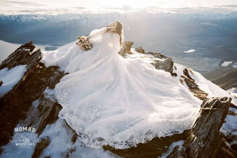 A bride, Mei, is sitting on top of a snow covered mountain during her wedding at Stoneridge Estate with Alex.