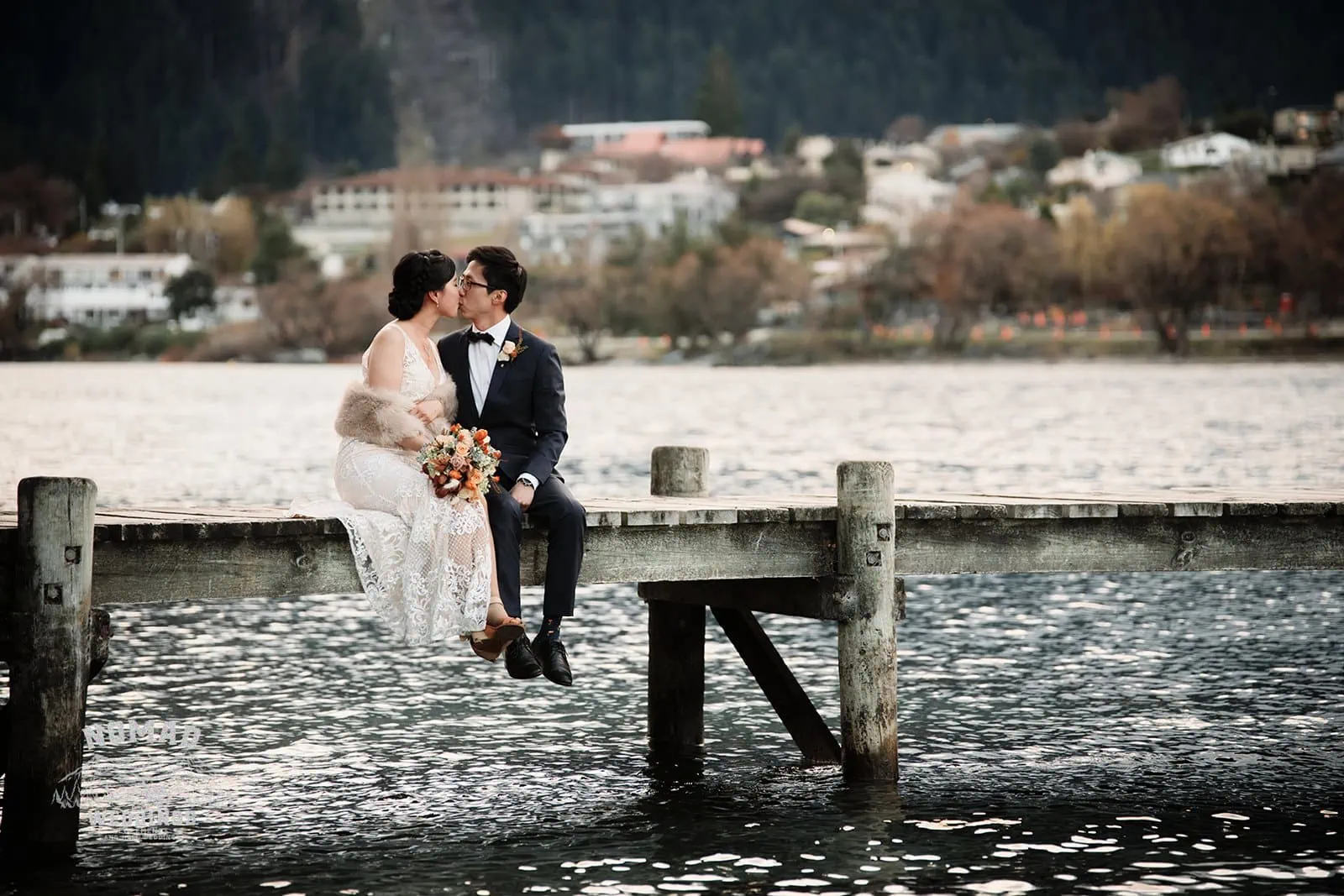 A pre-wedding shoot of Joanna and Tony, a bride and groom, sharing a romantic kiss on a dock in Queenstown, New Zealand.