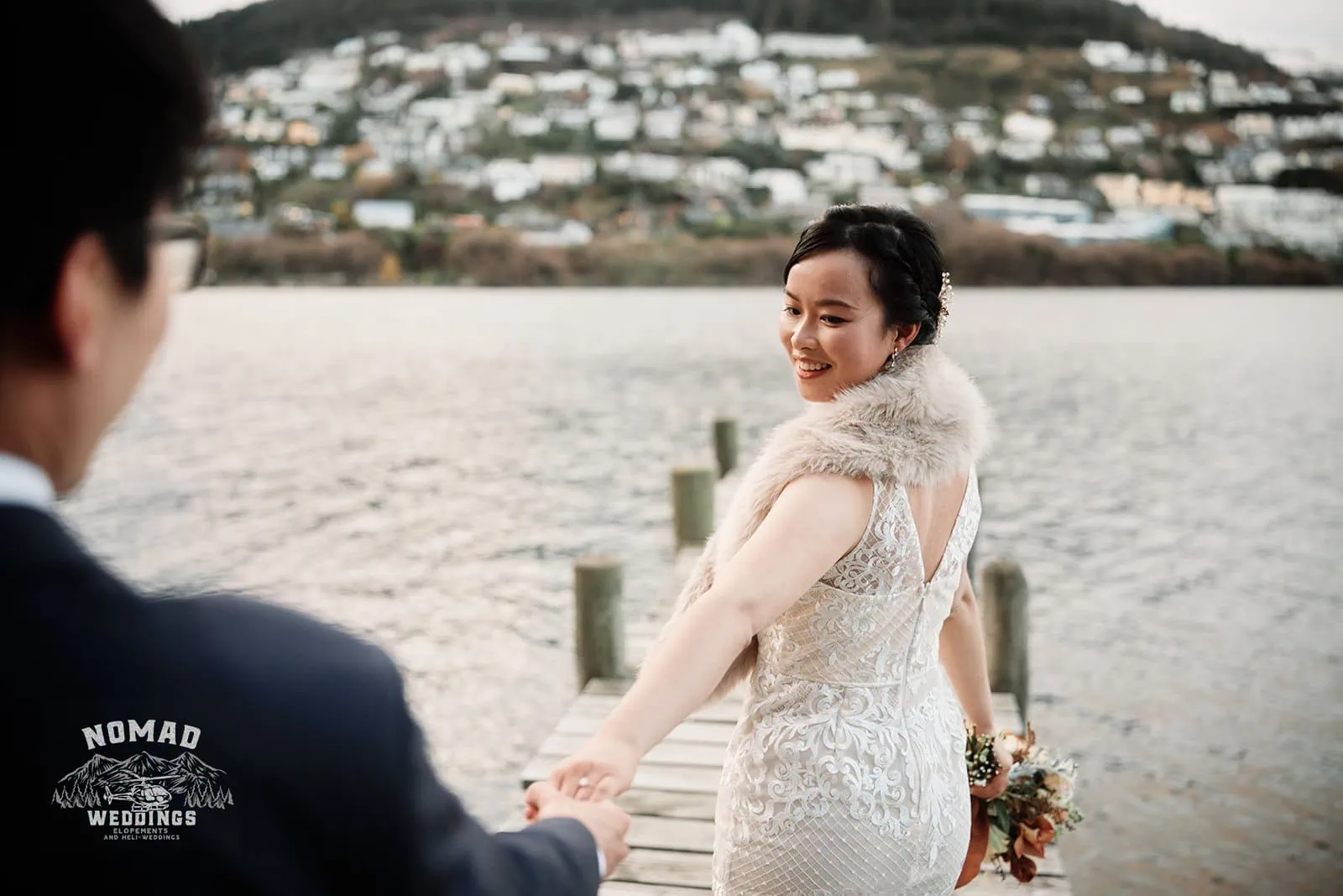 Joanna and Tony, a bride and groom, embrace on a dock during their pre-wedding shoot in Queenstown, New Zealand.