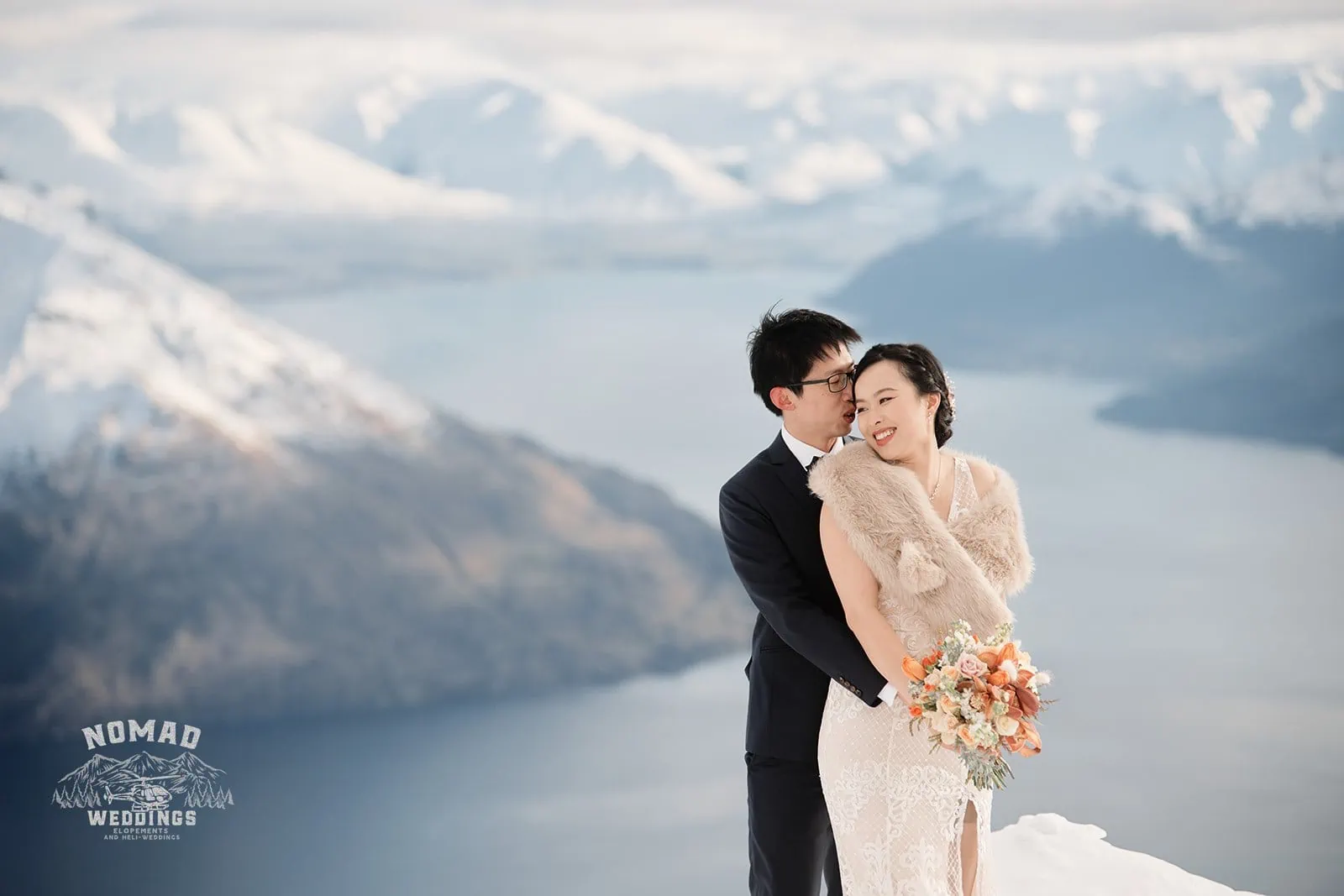 Joanna and Tony, the bride and groom, standing on top of a mountain in Queenstown, New Zealand.