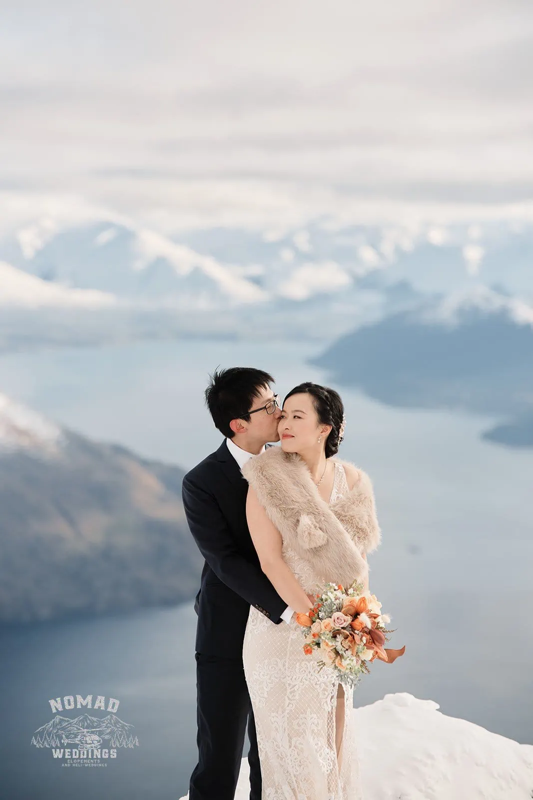 A bride and groom, Joanna and Tony, share a romantic kiss during their pre-wedding shoot in Queenstown, New Zealand's snowy mountains.
