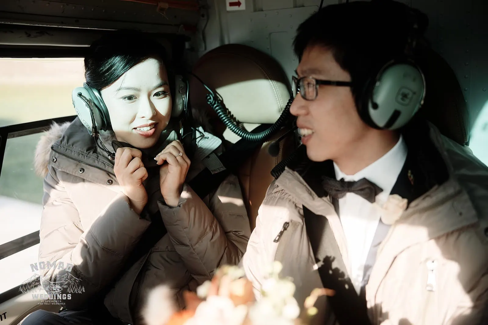 Joanna and Tony, a couple from New Zealand, posing for their pre-wedding shoot in Queenstown, wearing headphones inside a helicopter.