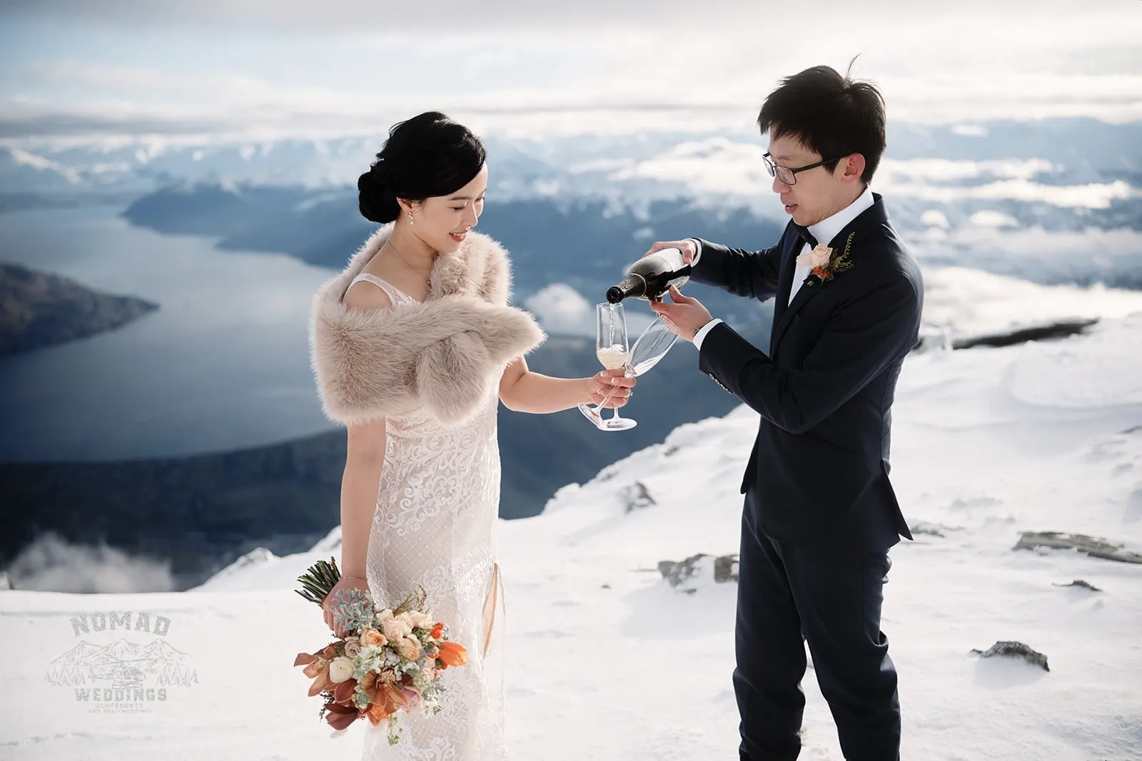 Joanna and Tony, a bride and groom from New Zealand, pouring wine during their pre-wedding shoot atop Queenstown's snowy mountain.