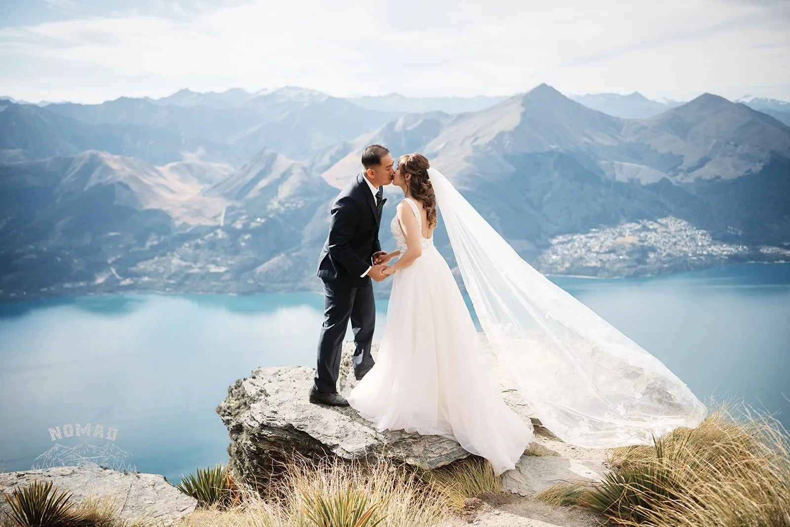 A couple, Nhi & Nicholas, pose on Cecil Peak for their pre-wedding shoot overlooking Lake Wanaka in Queenstown, NZ.