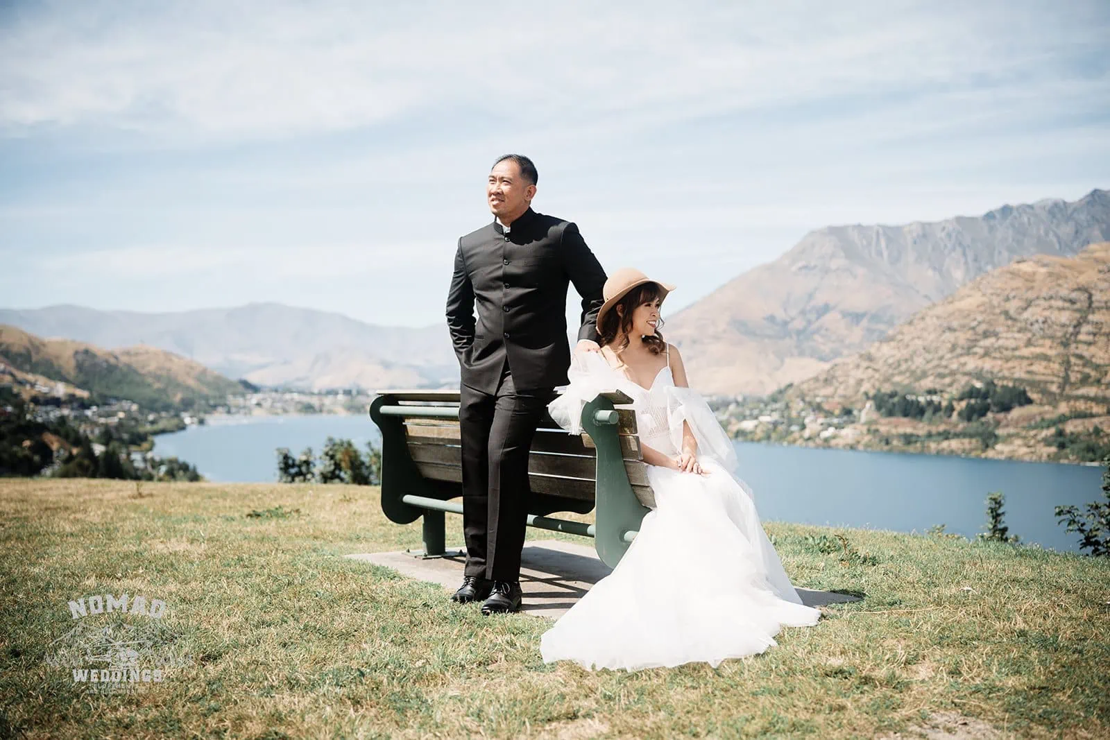 Nhi & Nicholas' Pre-Wedding Shoot in Queenstown, NZ captures a bride and groom sitting on a bench by a lake.