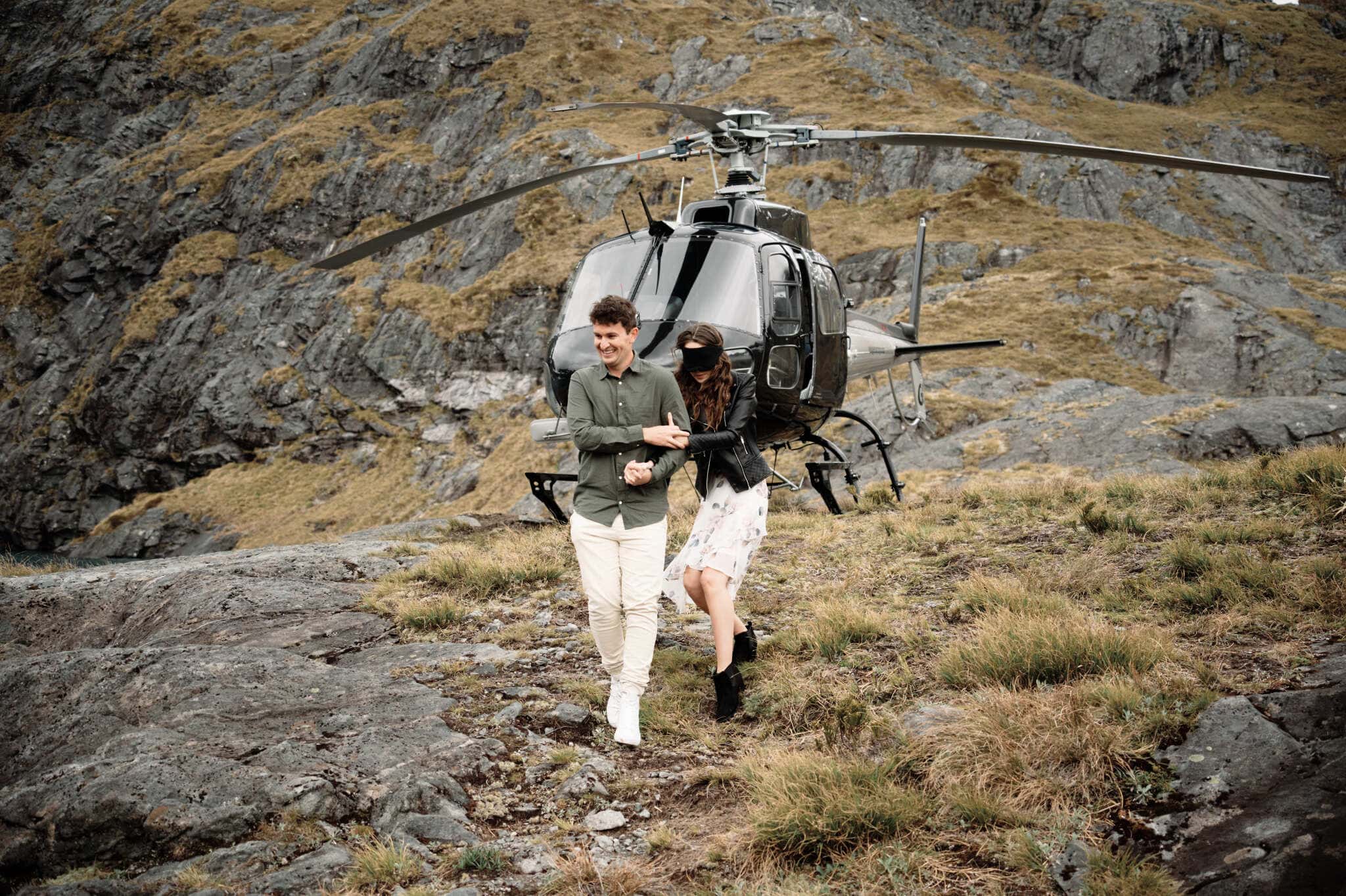 Scott and Hayley walking next to a helicopter in the mountains.