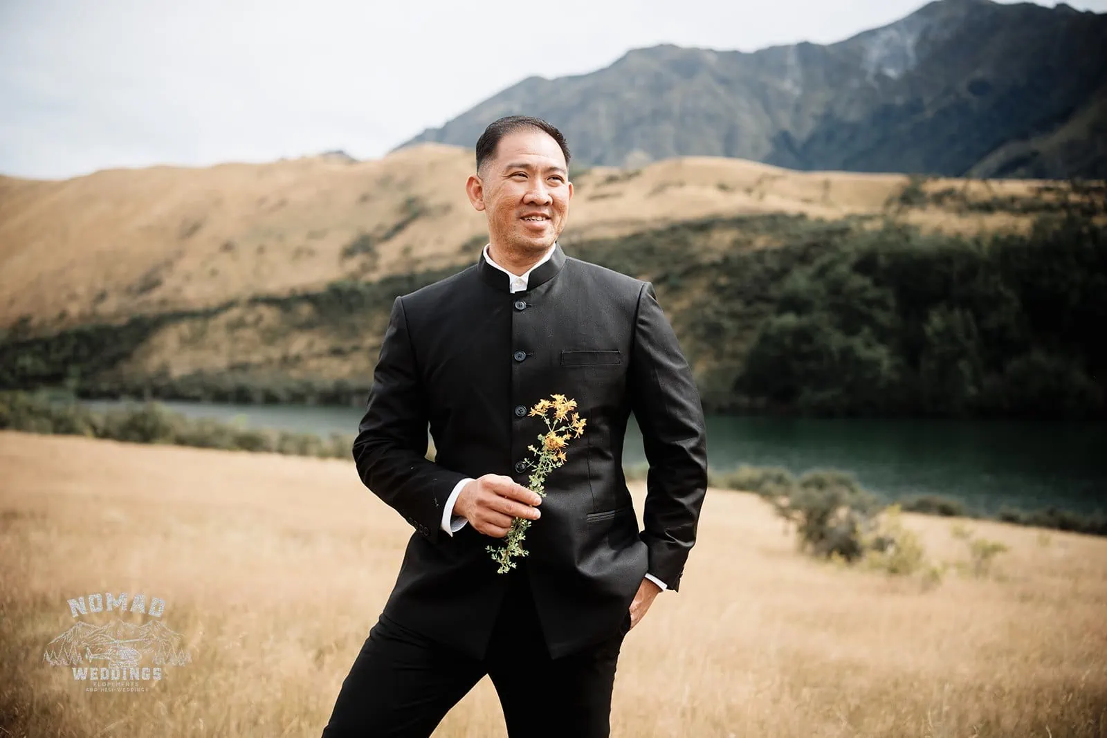 A man in a suit standing in a field during Nhi & Nicholas' Queenstown NZ pre-wedding shoot.