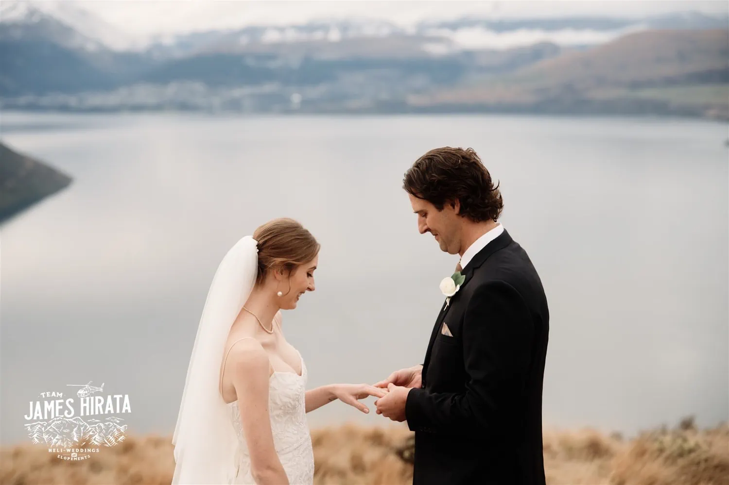 Hannah and Ross, an elopement wedding couple, exchange wedding rings on a hill overlooking Lake Wanaka in Queenstown, New Zealand.