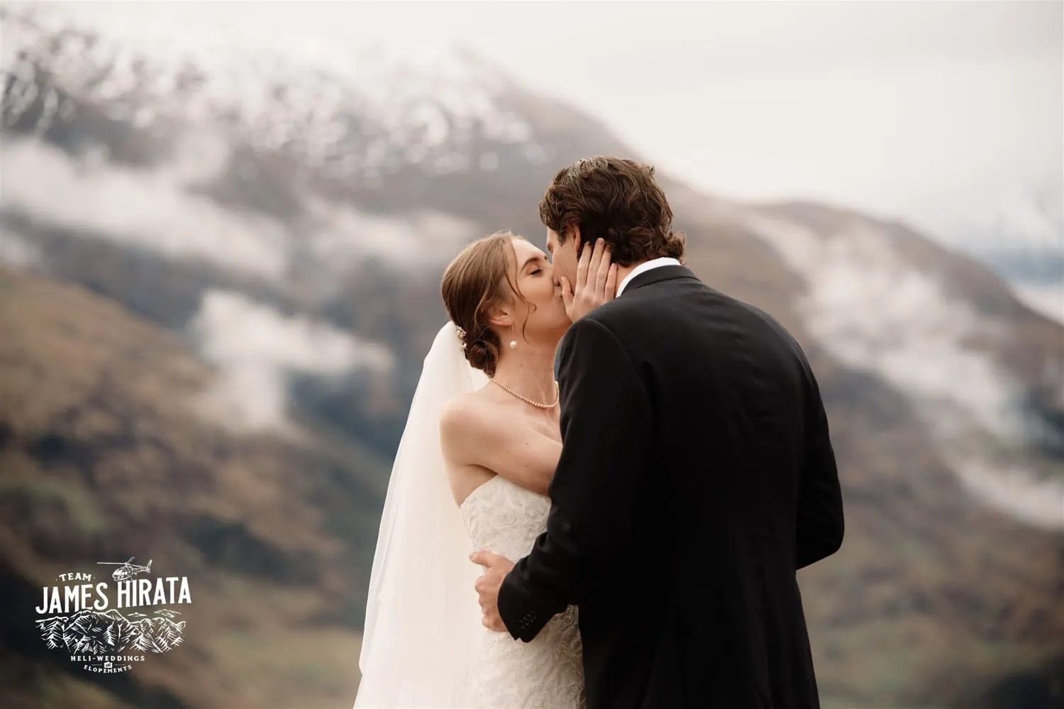 Hannah and Ross, an elopement wedding couple, sharing a kiss with Queenstown's mountains as their backdrop.