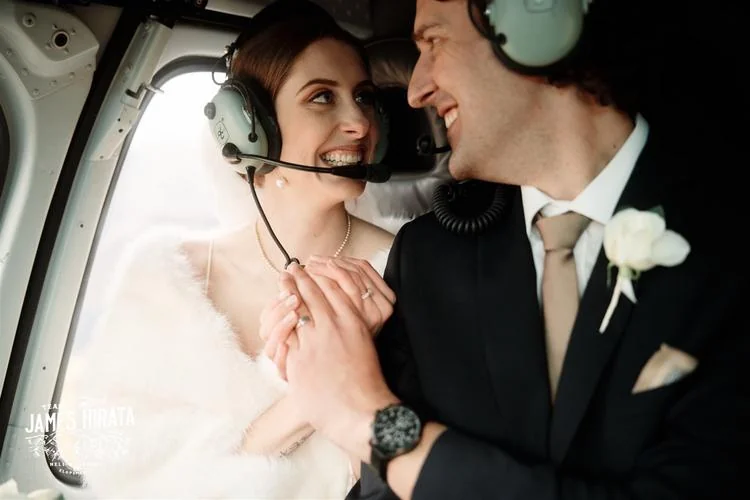 Hannah and Ross celebrate their elopement wedding in Queenstown, New Zealand, seated inside a helicopter cockpit.