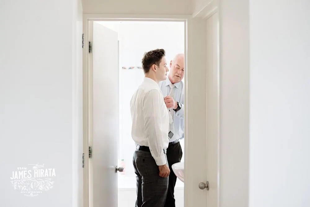 Jake, a man in a suit, talks to his dad in the doorway during their Queenstown elopement wedding.