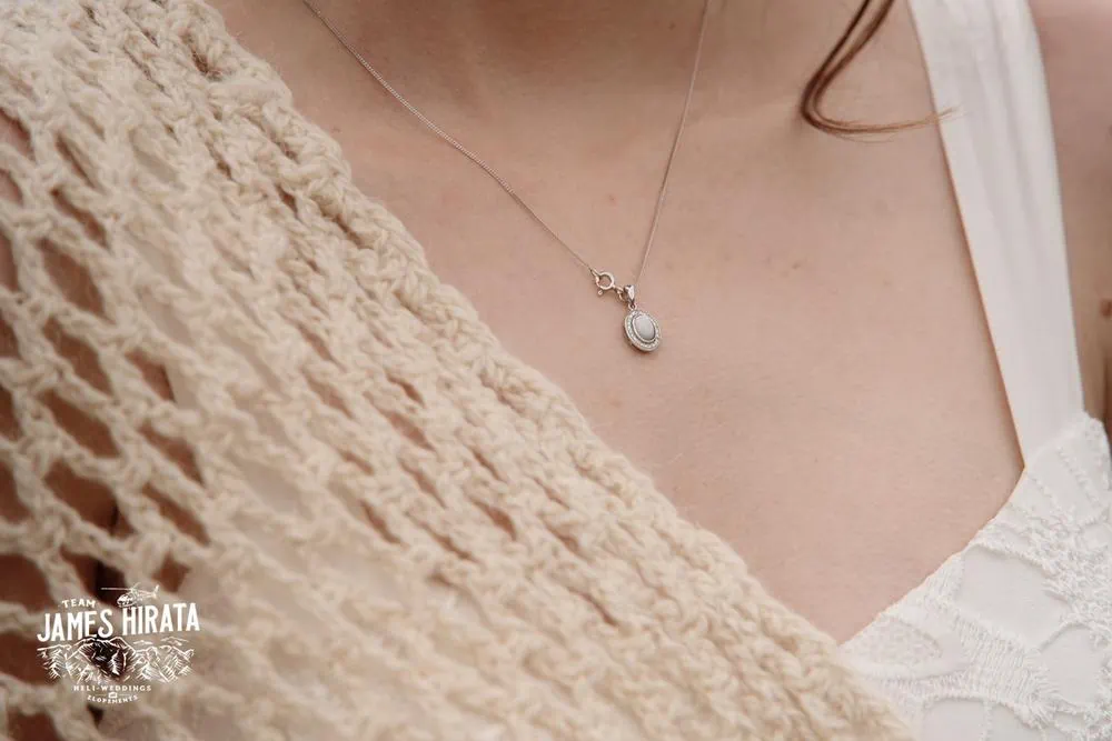 A woman is wearing a necklace with a pearl on it at her Queenstown elopement wedding.