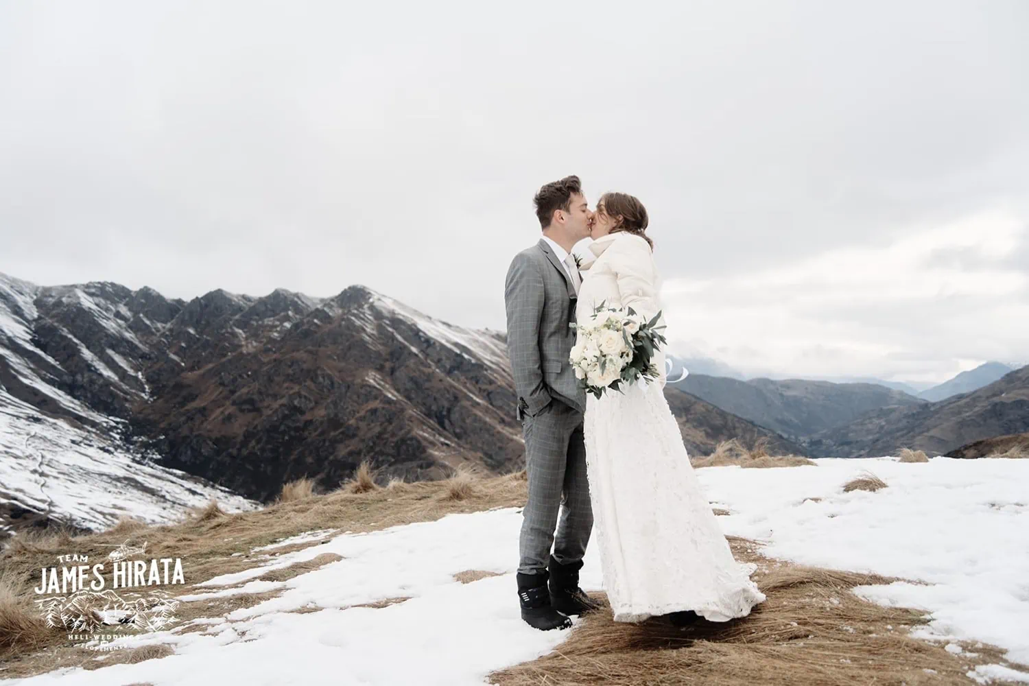 Regan & Jake sharing a passionate kiss during their Queenstown elopement on a snow covered mountain.
