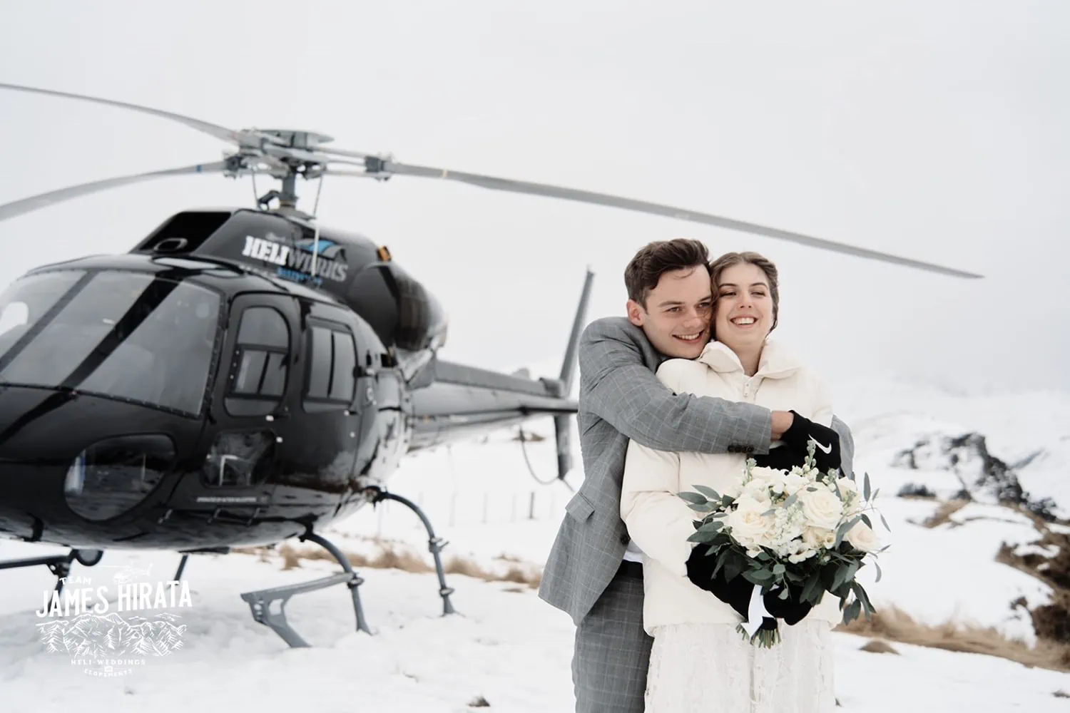 A Regan and Jake embracing in front of a helicopter during their Queenstown elopement wedding.