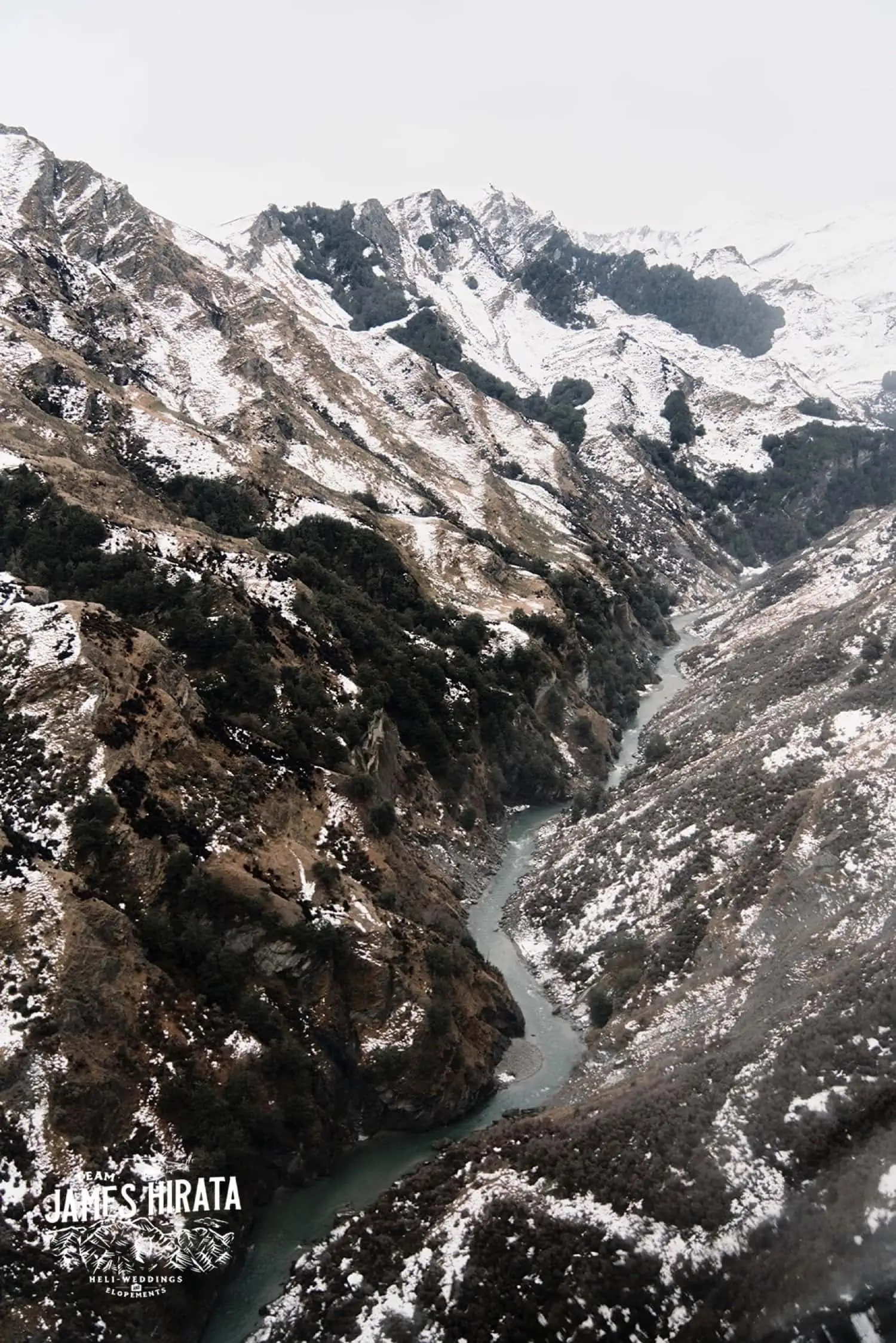 Regan & Jake's elopement wedding in Queenstown with an aerial view of snow covered mountains and a river.