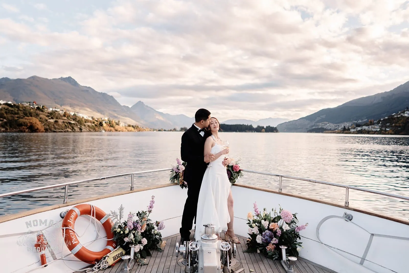 A bride and groom share a passionate kiss on the bow of a boat at Lake Wanaka, creating an unforgettable moment.