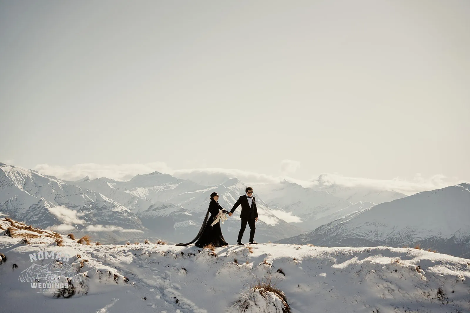 A couple atop a snow-laden peak.
