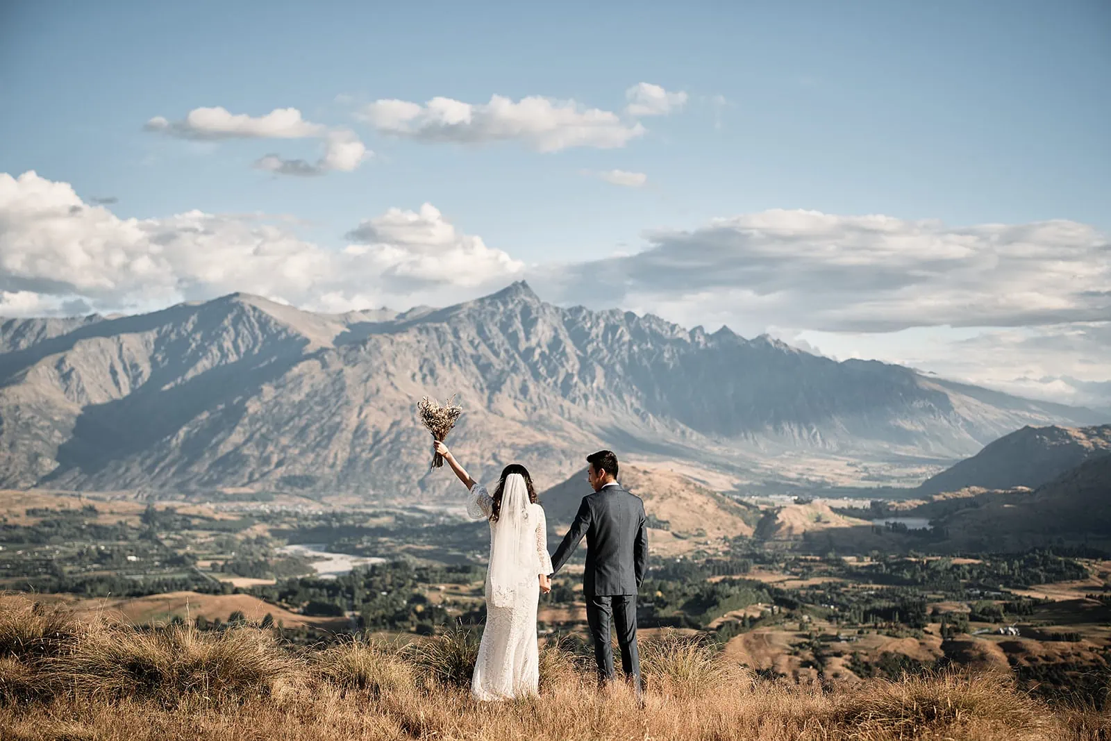 Coronet Peak Queenstown New Zealand Elopement Wedding Photographer - A bride and groom standing on top of Coronet Peak, Queenstown, with mountains in the background.