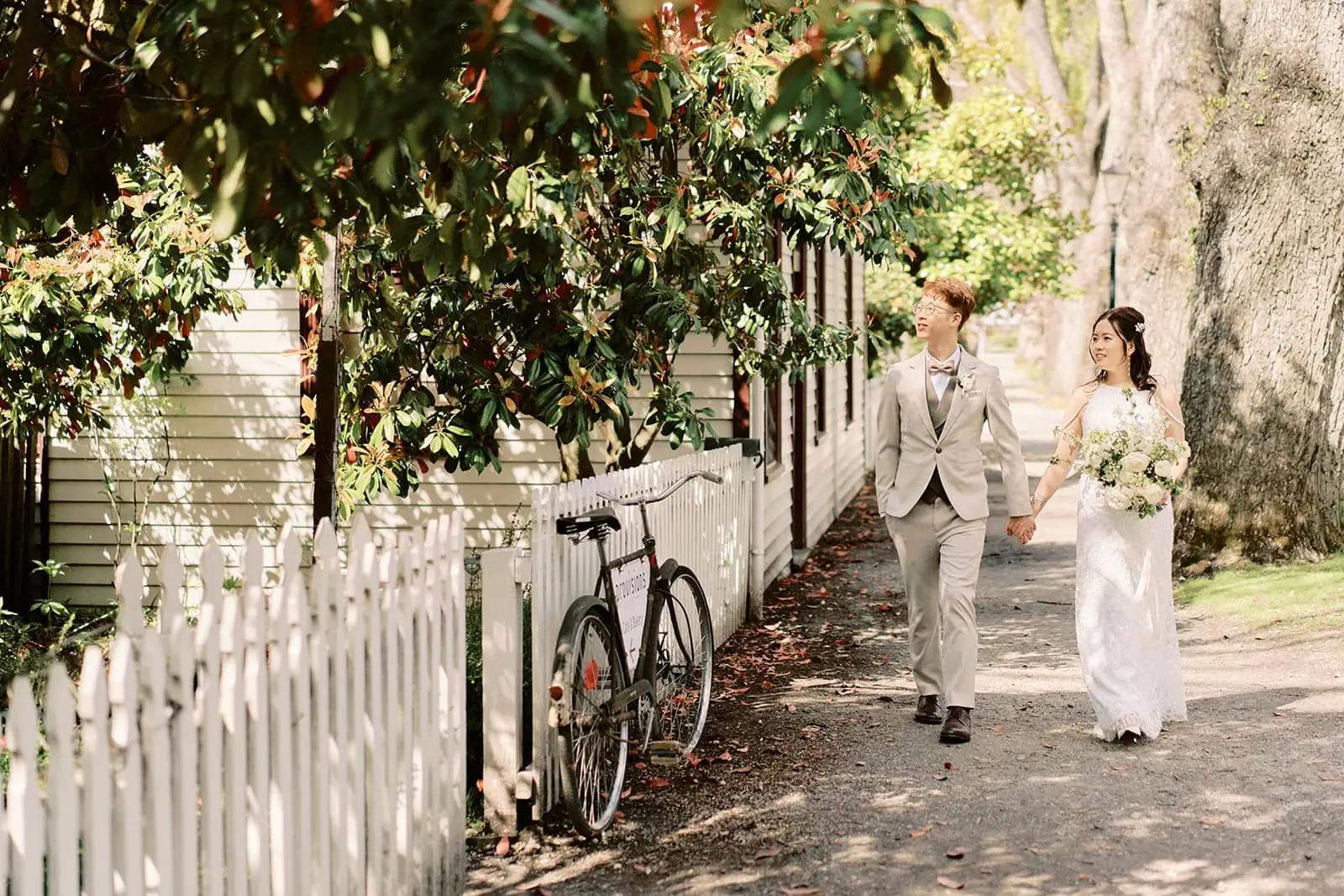 Queenstown New Zealand Elopement Wedding Photographer - A summer bride and groom walking down a street in Queenstown accompanied by a bicycle as their guide.