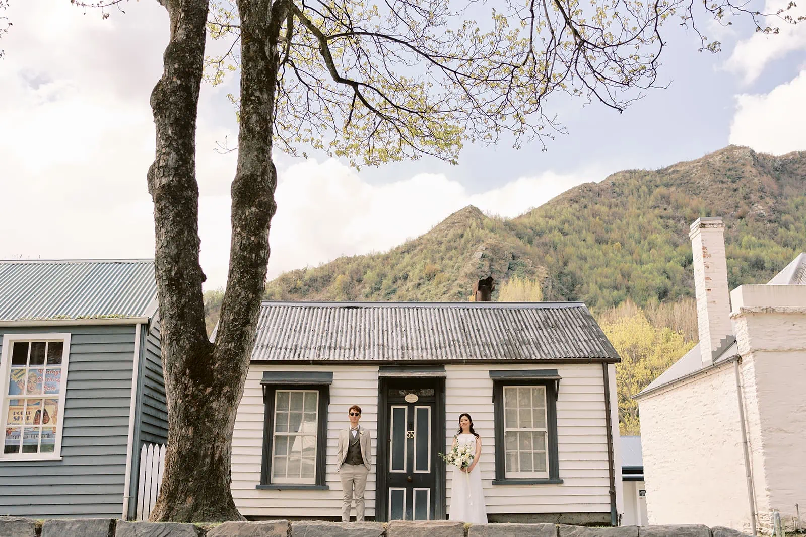 Queenstown New Zealand Elopement Wedding Photographer - A bride and groom standing in front of a house in Queenstown during the summer.