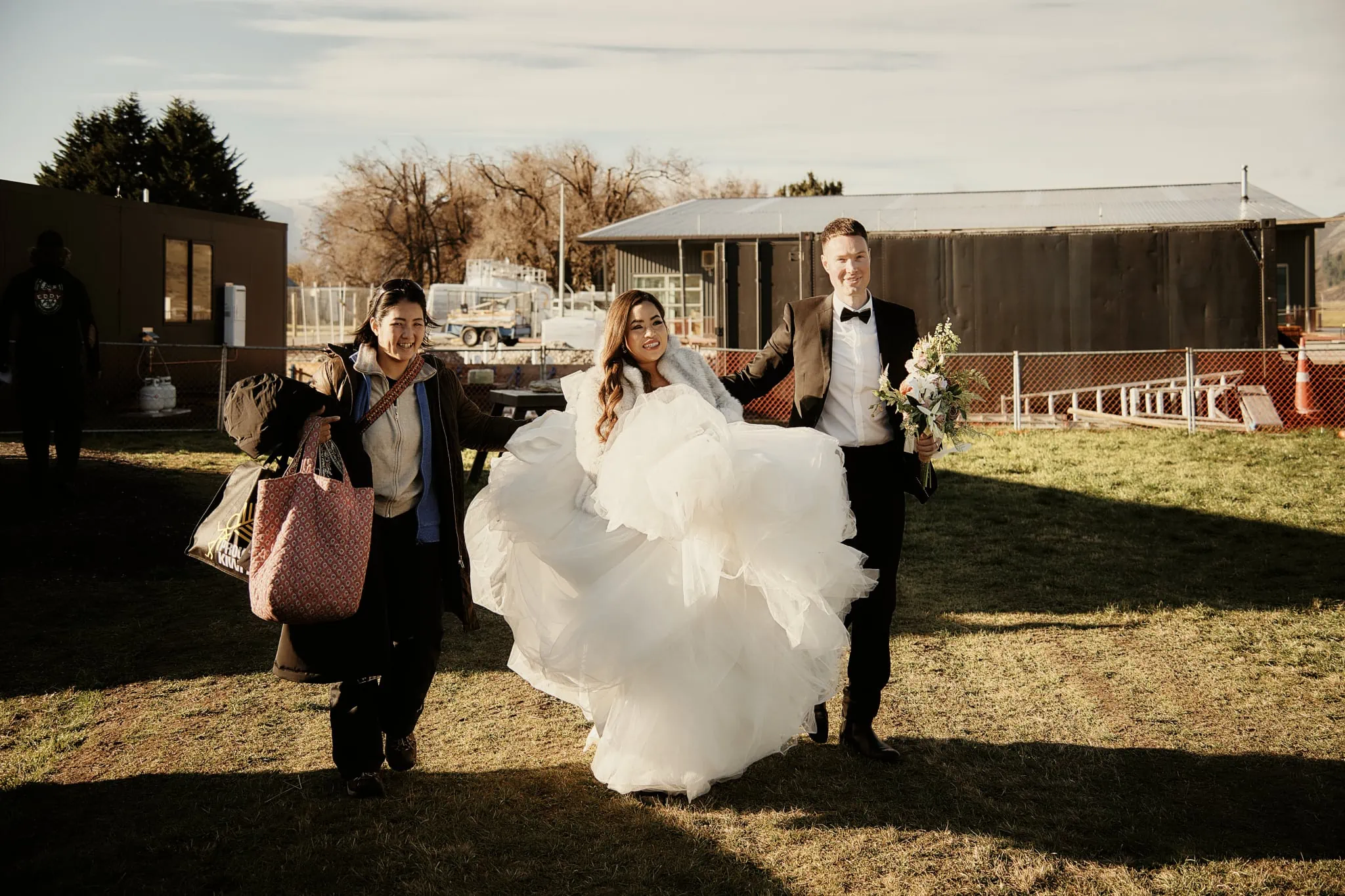 Queenstown New Zealand Elopement Wedding Photographer - Amy and Callum have a Queenstown Heli Pre Wedding Shoot, walking through a grassy field.