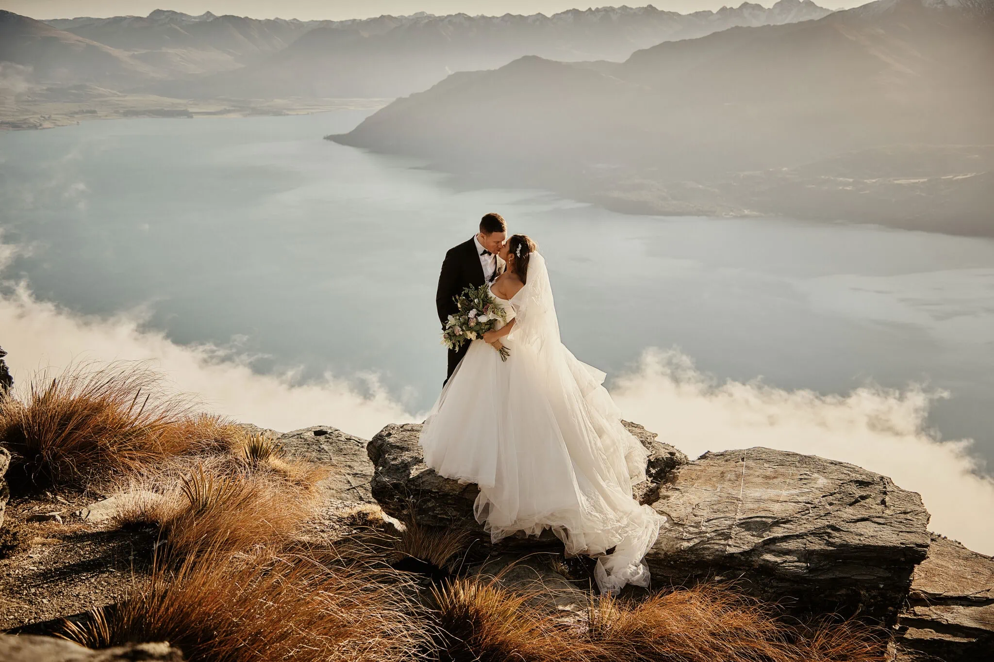 Queenstown New Zealand Elopement Wedding Photographer - Amy and Callum, a bride and groom, posing on a mountaintop during their Queenstown Heli Pre Wedding Shoot.