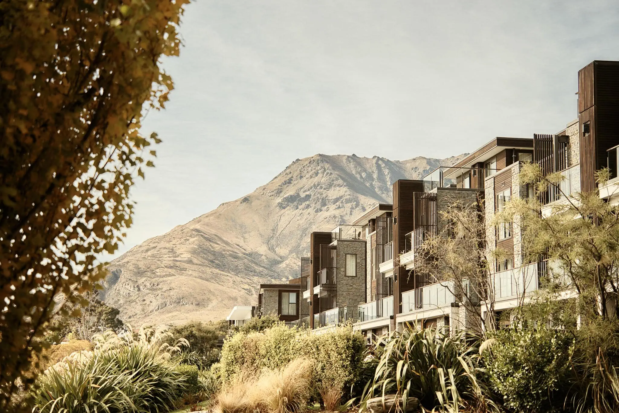 Queenstown New Zealand Elopement Wedding Photographer - A scenic view of a mountain in front of a row of houses during Sarah and Tim's Heli Elopement Wedding in Queenstown.