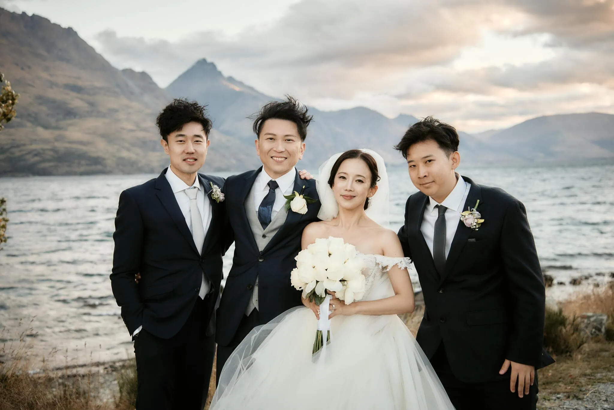 Queenstown New Zealand Elopement Wedding Photographer - Four asian bridesmaids posing for a photo in front of a scenic Queenstown lake during Sarah and Tim's heli elopement wedding.