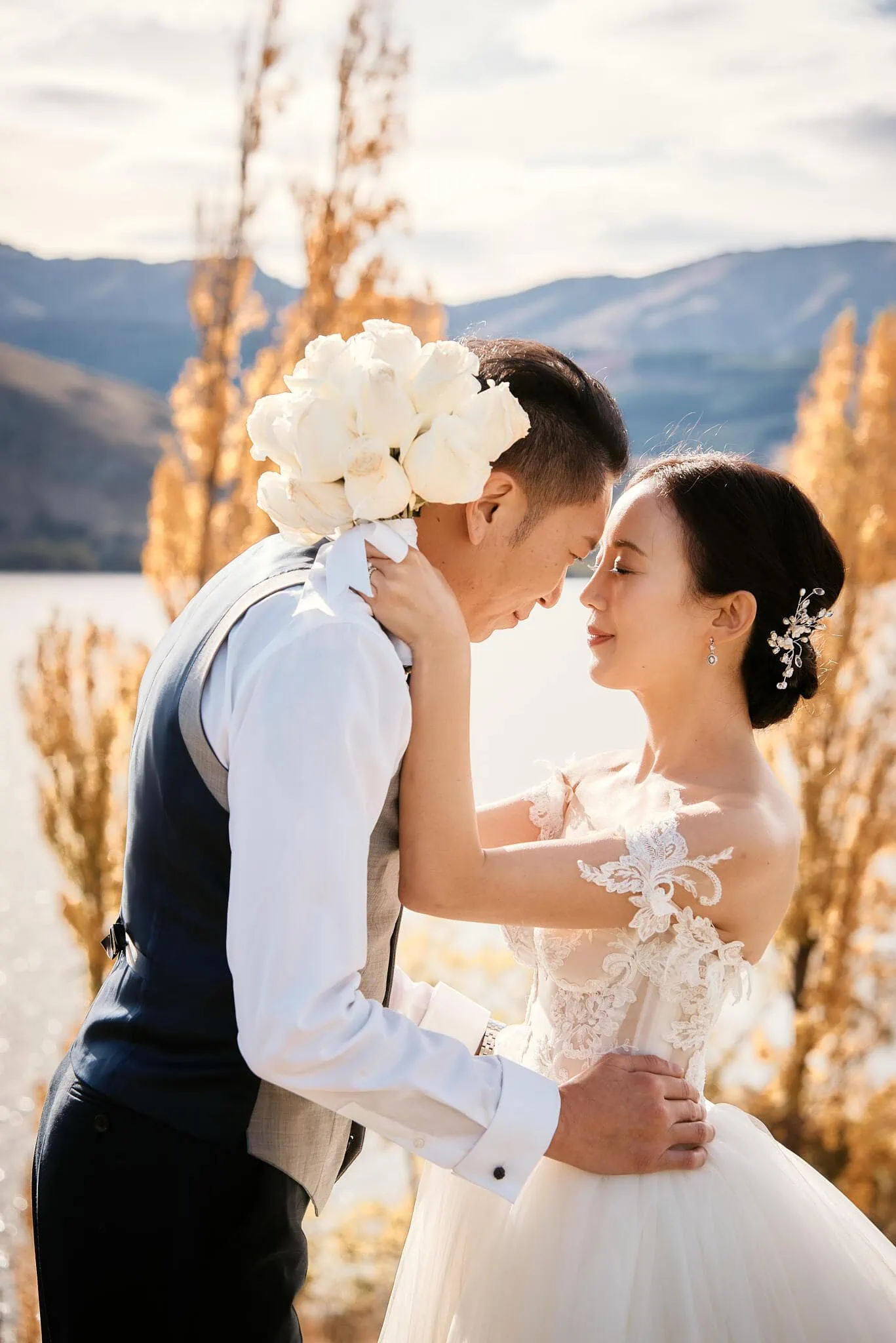 Queenstown New Zealand Elopement Wedding Photographer - Sarah and Tim sharing an intimate moment during their Scenic Queenstown Heli Elopement Wedding, embraced in front of a picturesque lake.