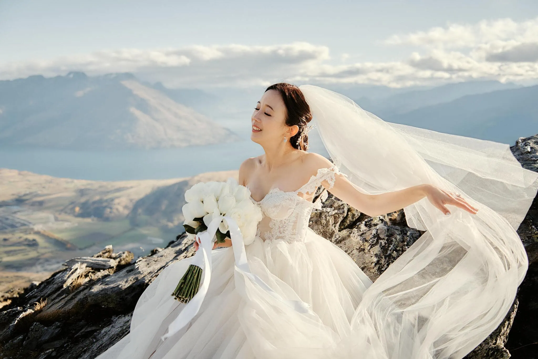 Queenstown New Zealand Elopement Wedding Photographer - Sarah and Tim's scenic Queenstown heli elopement wedding captures the bride sitting on a mountain with her wedding veil.