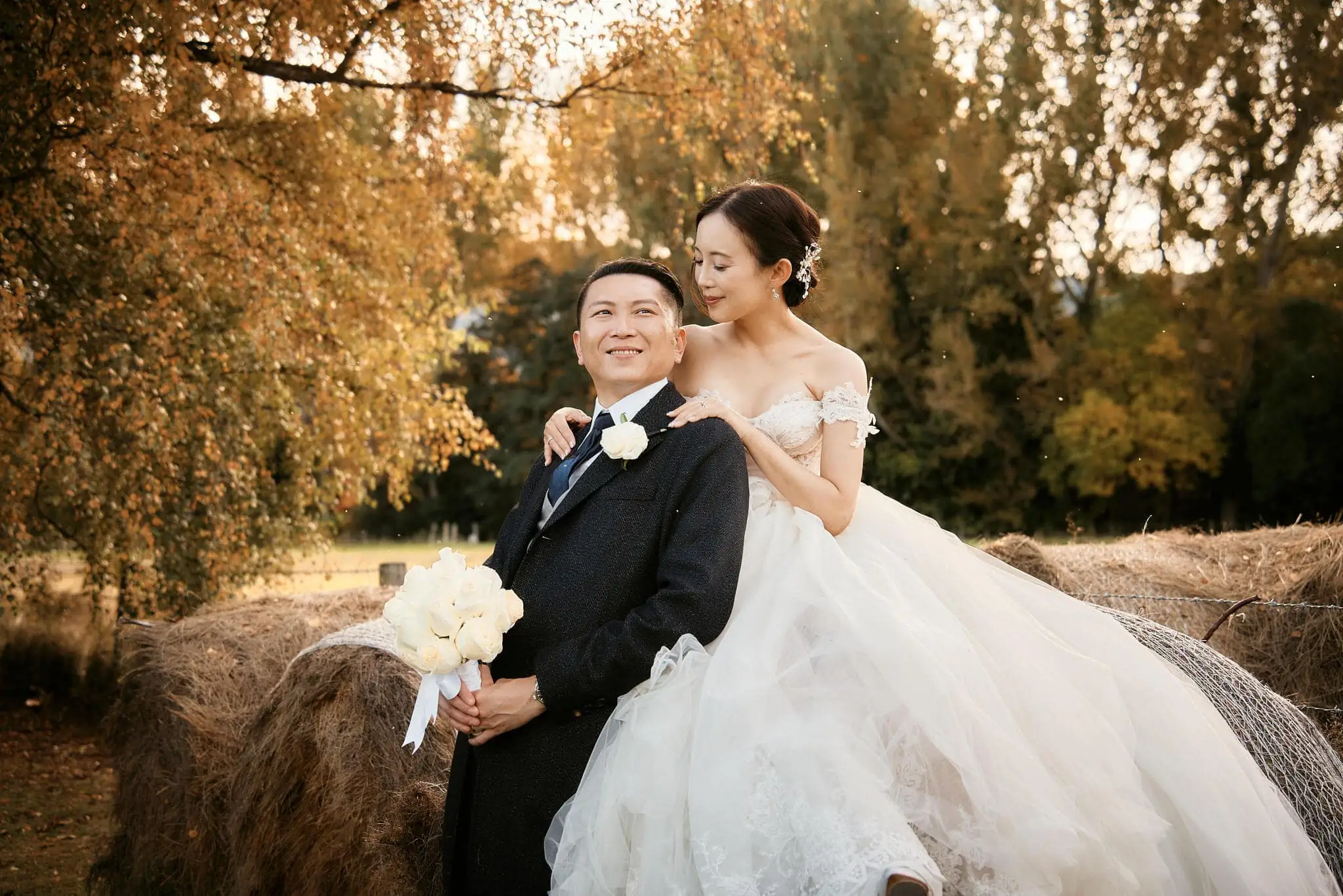 Queenstown New Zealand Elopement Wedding Photographer - Sarah and Tim, a bride and groom, posing for their scenic Queenstown heli elopement wedding in front of hay bales.