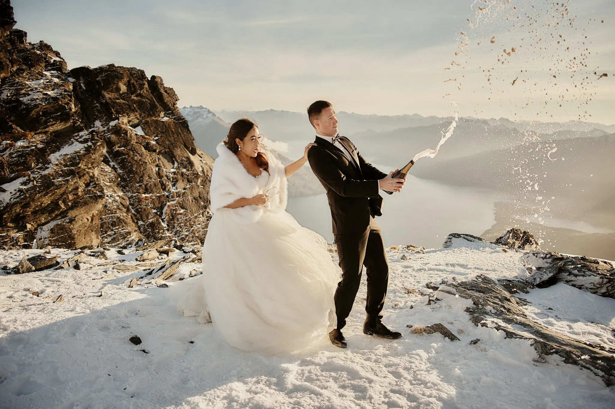 Queenstown New Zealand Elopement Wedding Photographer - Amy and Callum blowing bubbles during their Queenstown Heli Pre Wedding Shoot on a snowy mountain.