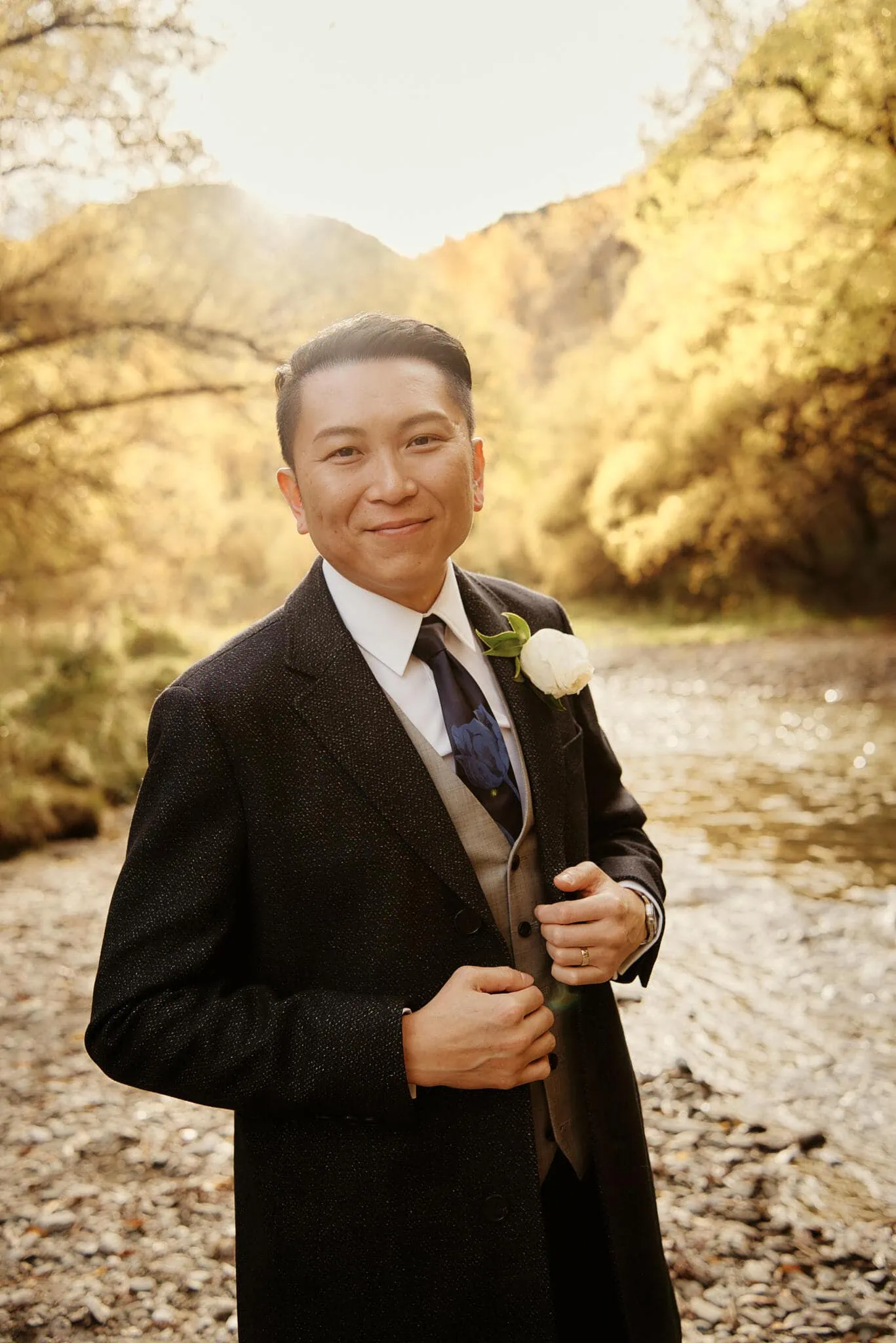Queenstown New Zealand Elopement Wedding Photographer - A man in a suit standing next to a scenic river during Sarah and Tim's Queenstown elopement.