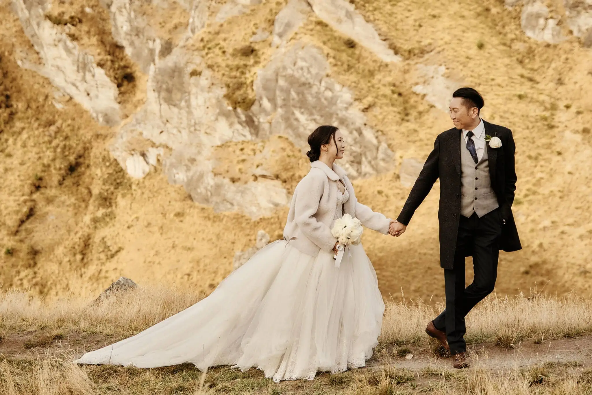Queenstown New Zealand Elopement Wedding Photographer - Sarah and Tim holding hands in Scenic Queenstown Heli Elopement Wedding with a mountain backdrop.