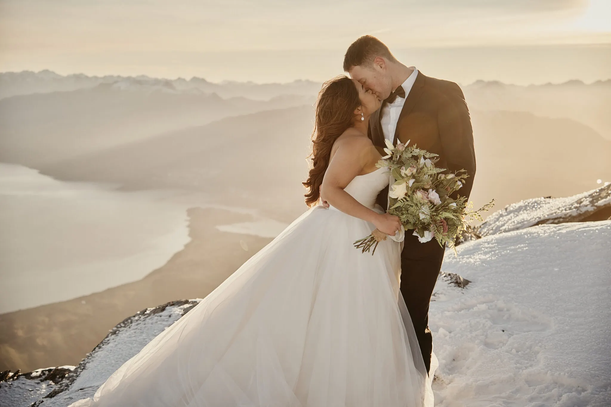 Queenstown New Zealand Elopement Wedding Photographer - Amy and Callum's romantic Queenstown Heli Pre Wedding Shoot captures a snowy mountain kiss.