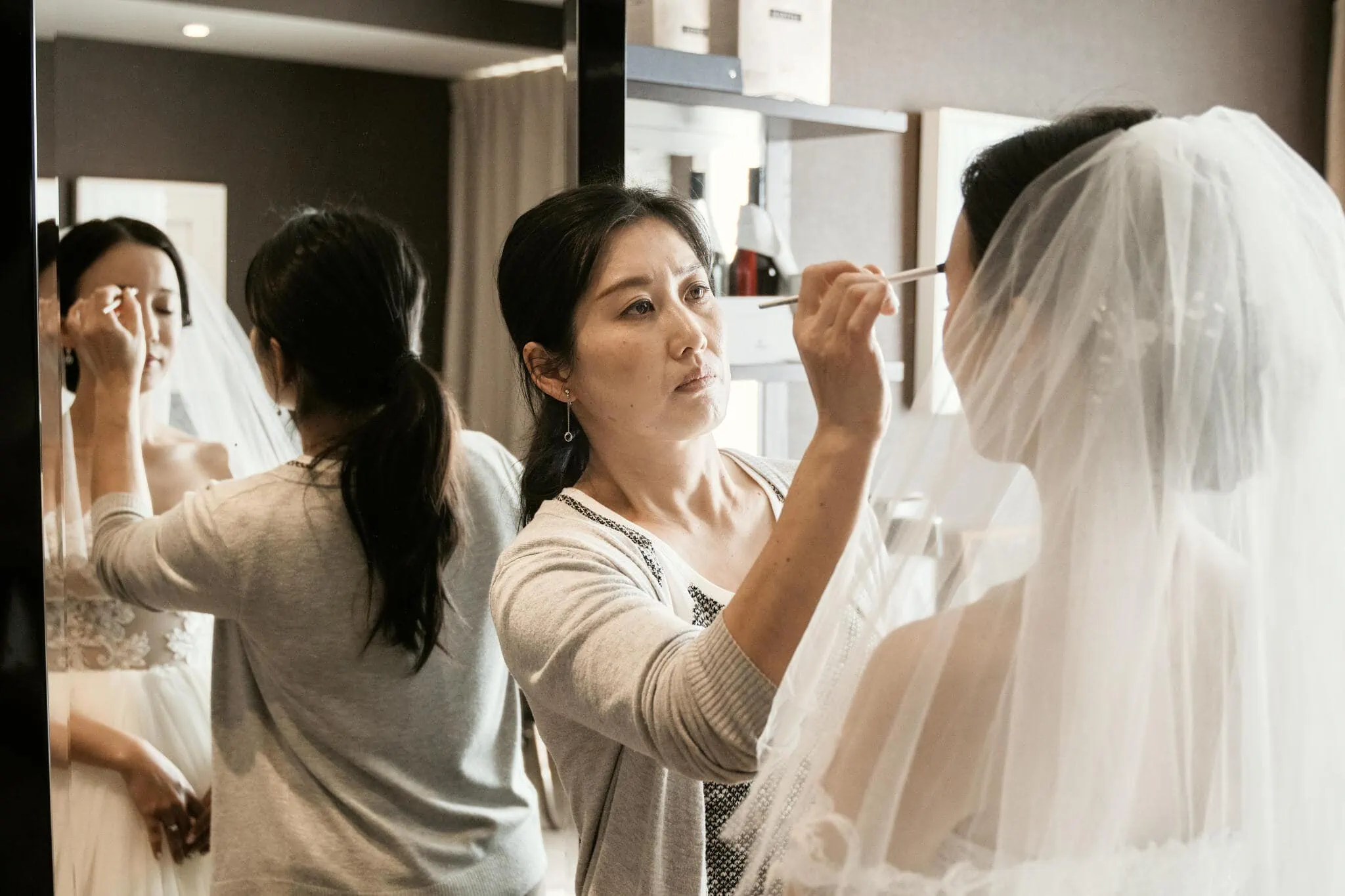 Queenstown New Zealand Elopement Wedding Photographer - A bride, Sarah, getting her makeup done in front of a mirror at their scenic Queenstown heli elopement wedding.