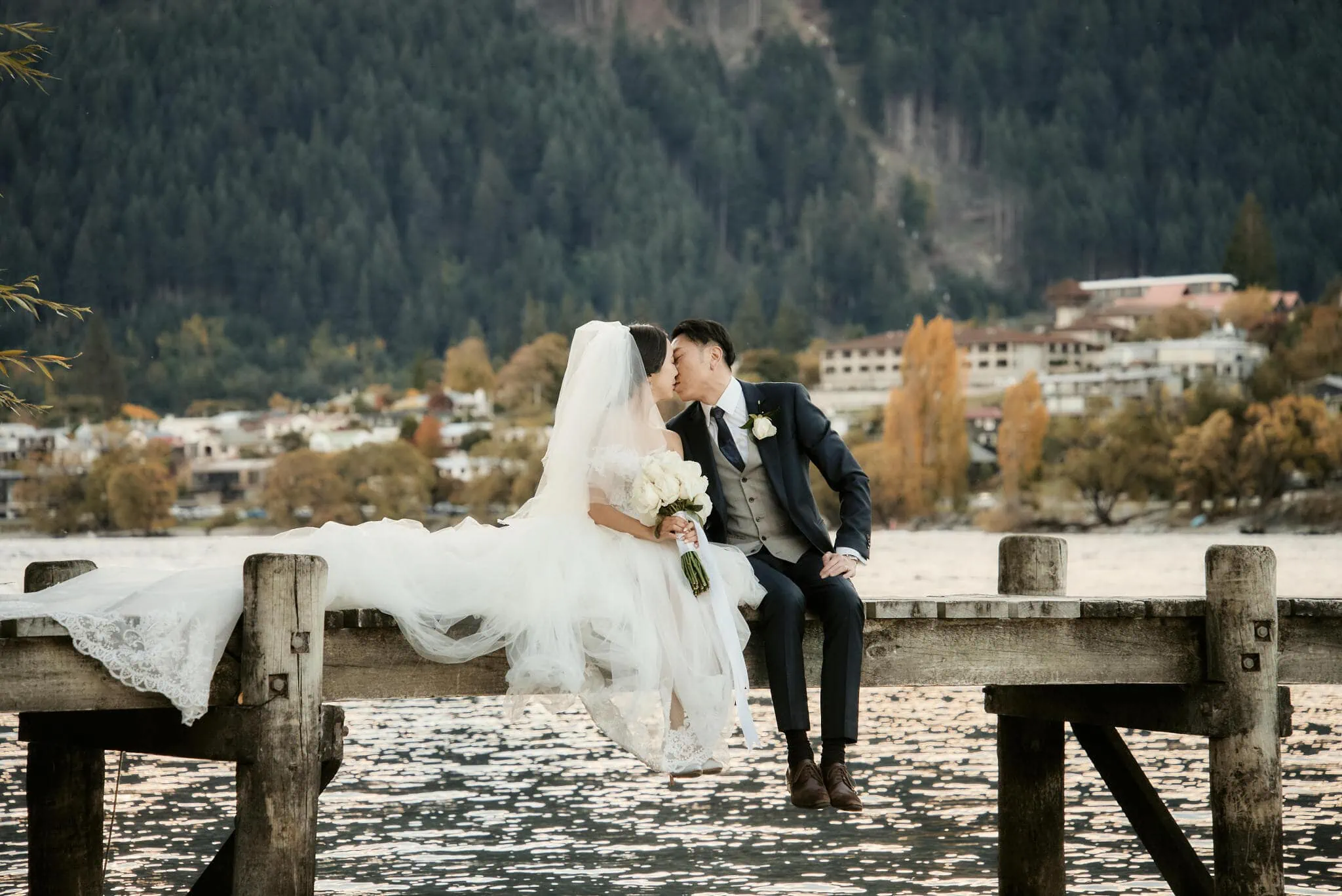 Queenstown New Zealand Elopement Wedding Photographer - Sarah and Tim sharing a kiss during their Scenic Queenstown Heli Elopement Wedding on a dock with mountains in the background.