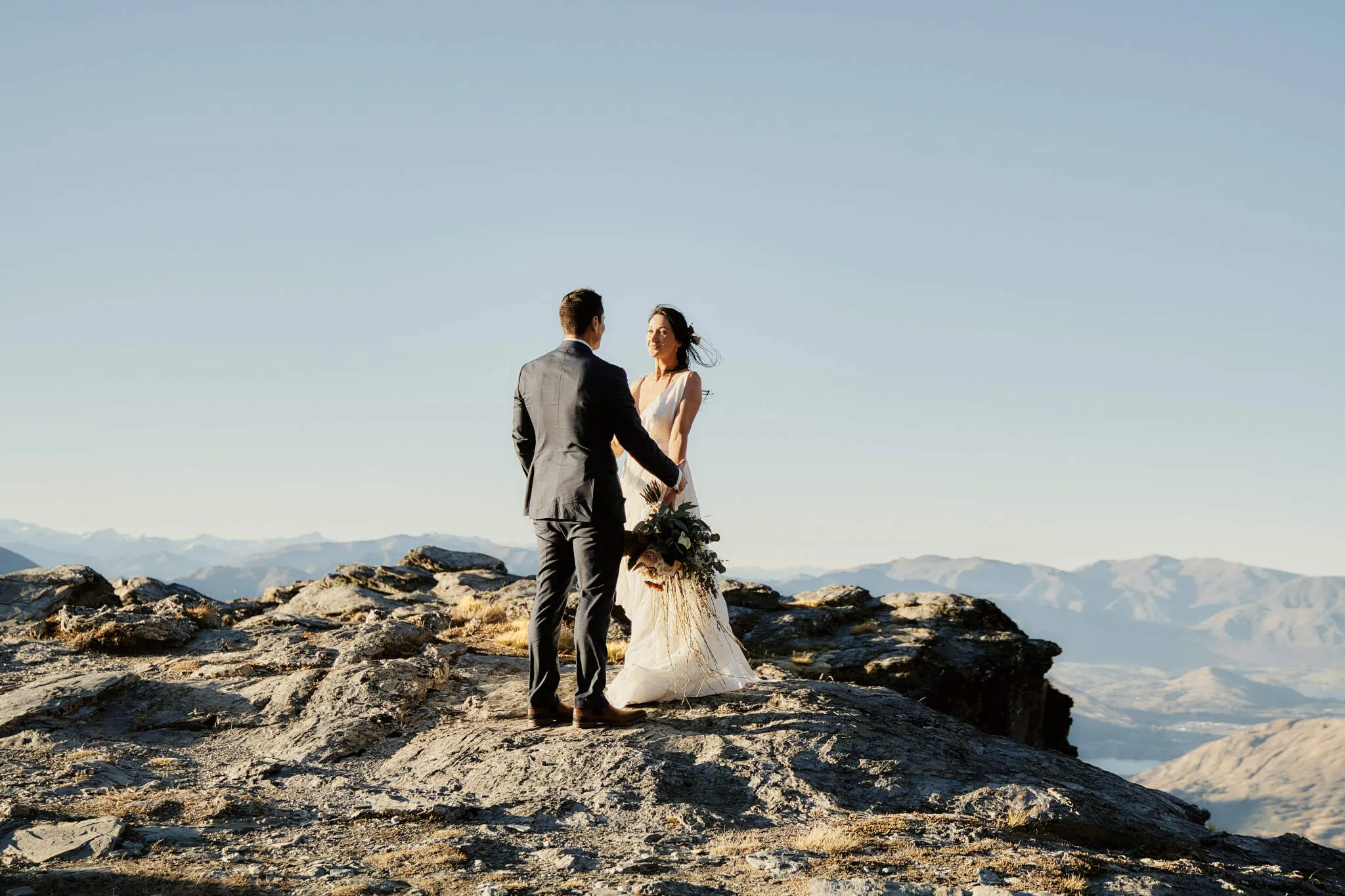 Queenstown New Zealand Elopement Wedding Photographer - Sarah and Bobby's Queenstown Heli Elopement Wedding portrays a couple standing on top of a mountain in New Zealand.