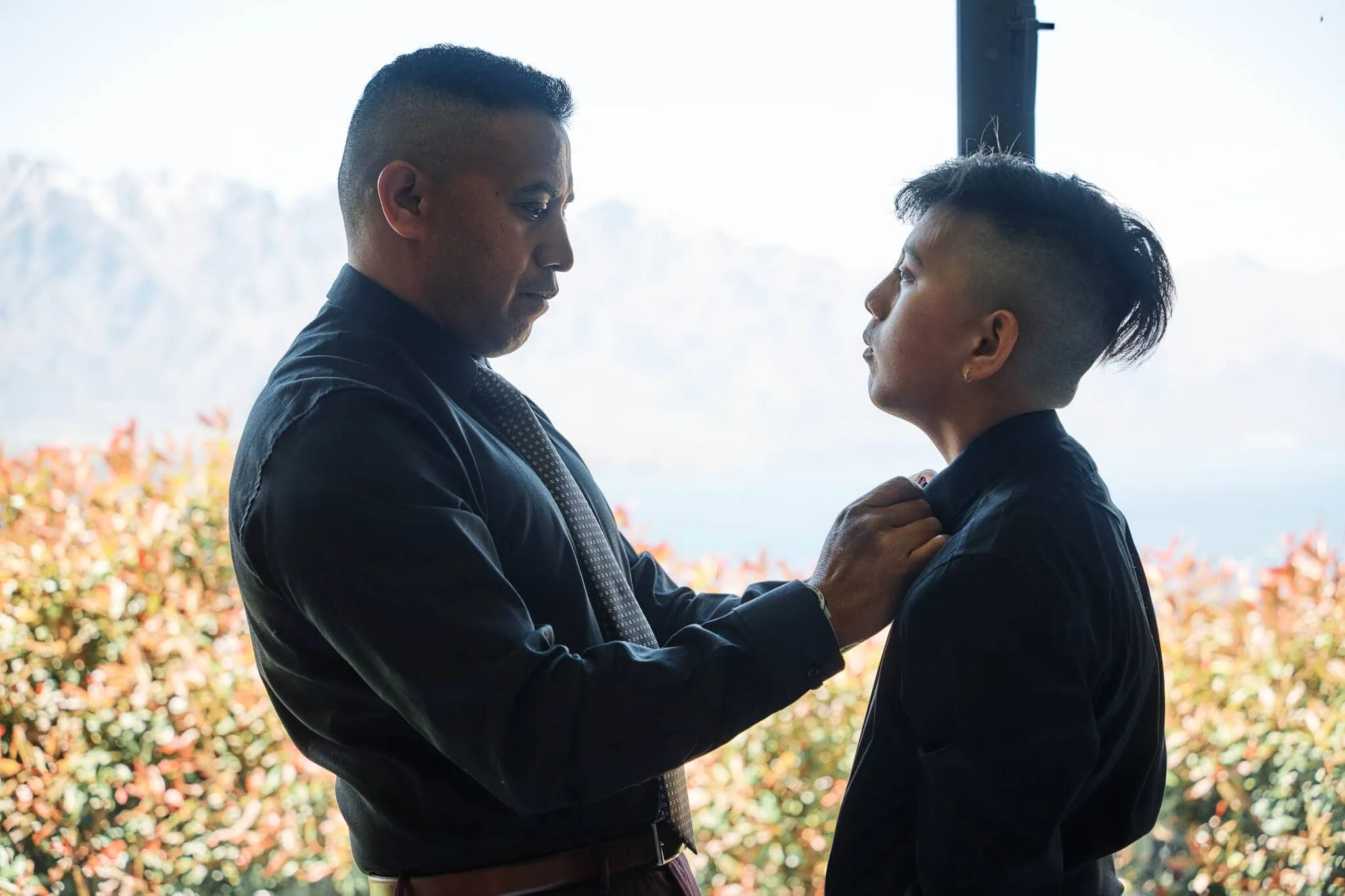 Queenstown New Zealand Elopement Wedding Photographer - A man is adjusting Nikita's tie in front of Coromandel Peak.