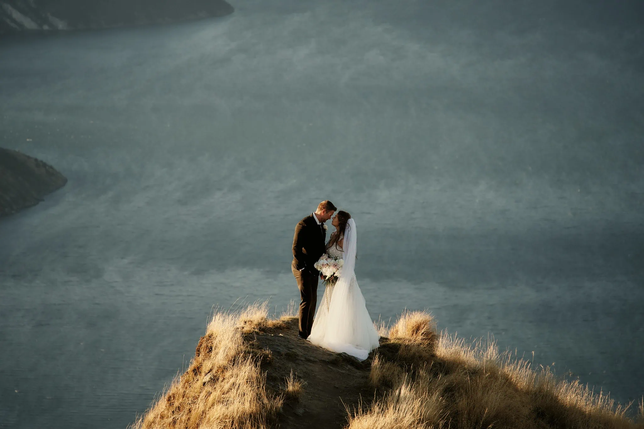 Queenstown New Zealand Elopement Wedding Photographer - Ashleigh and Anthony's Roy's Peak Heli Elopement Wedding on top of a cliff overlooking a lake.