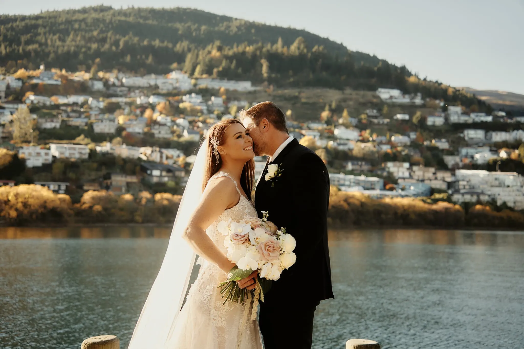Queenstown New Zealand Elopement Wedding Photographer - Ashleigh and Anthony share a romantic kiss at Roy's Peak overlooking a picturesque lake during their New Zealand heli elopement wedding.
