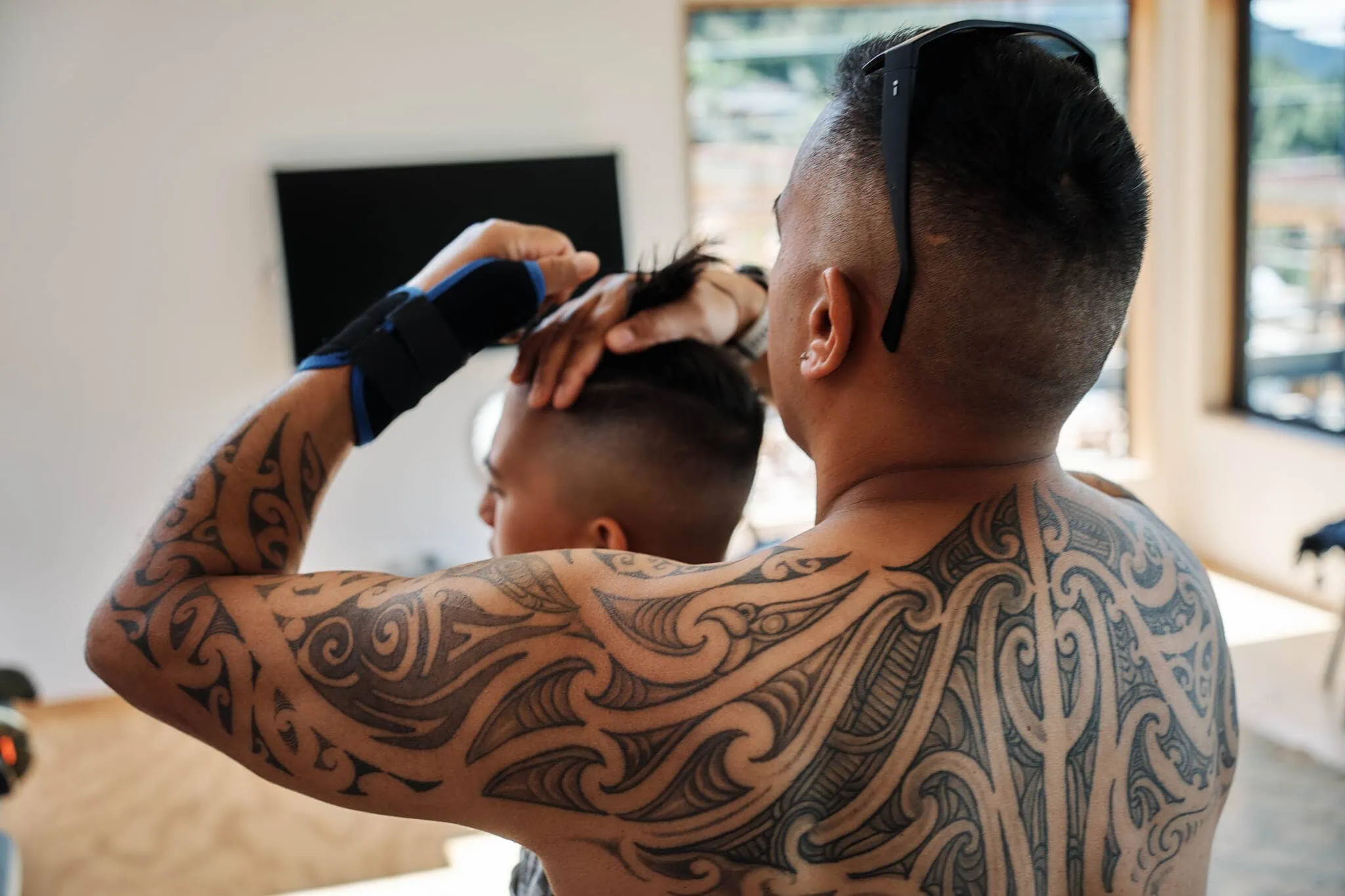 Queenstown New Zealand Elopement Wedding Photographer - A man with a tattoo is getting his son's hair done at the Coromandel Peak Heli Elopement Wedding.