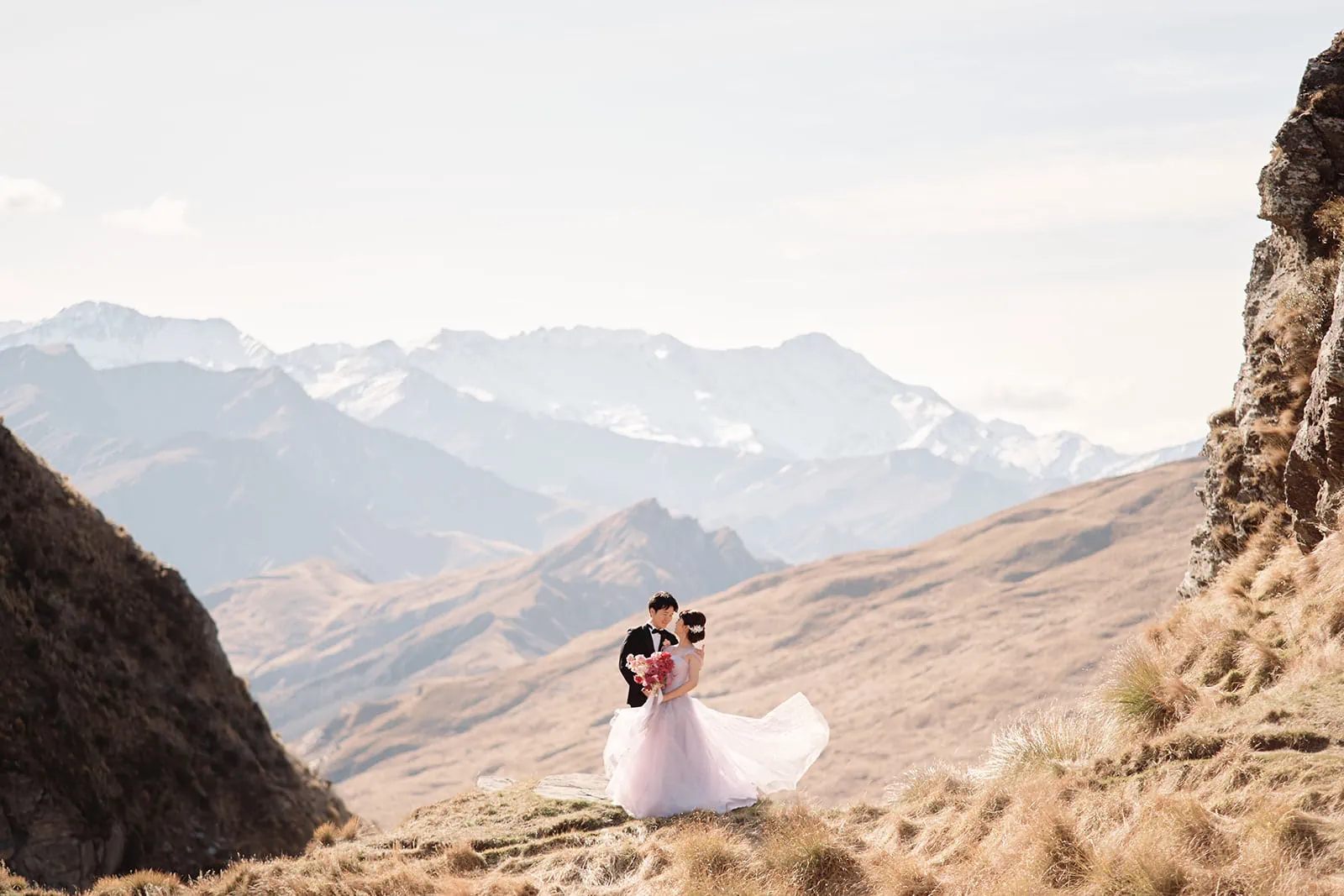 Queenstown New Zealand Elopement Wedding Photographer - A summer bride and groom standing on the side of a mountain in Queenstown, with breathtaking mountainous backgrounds.